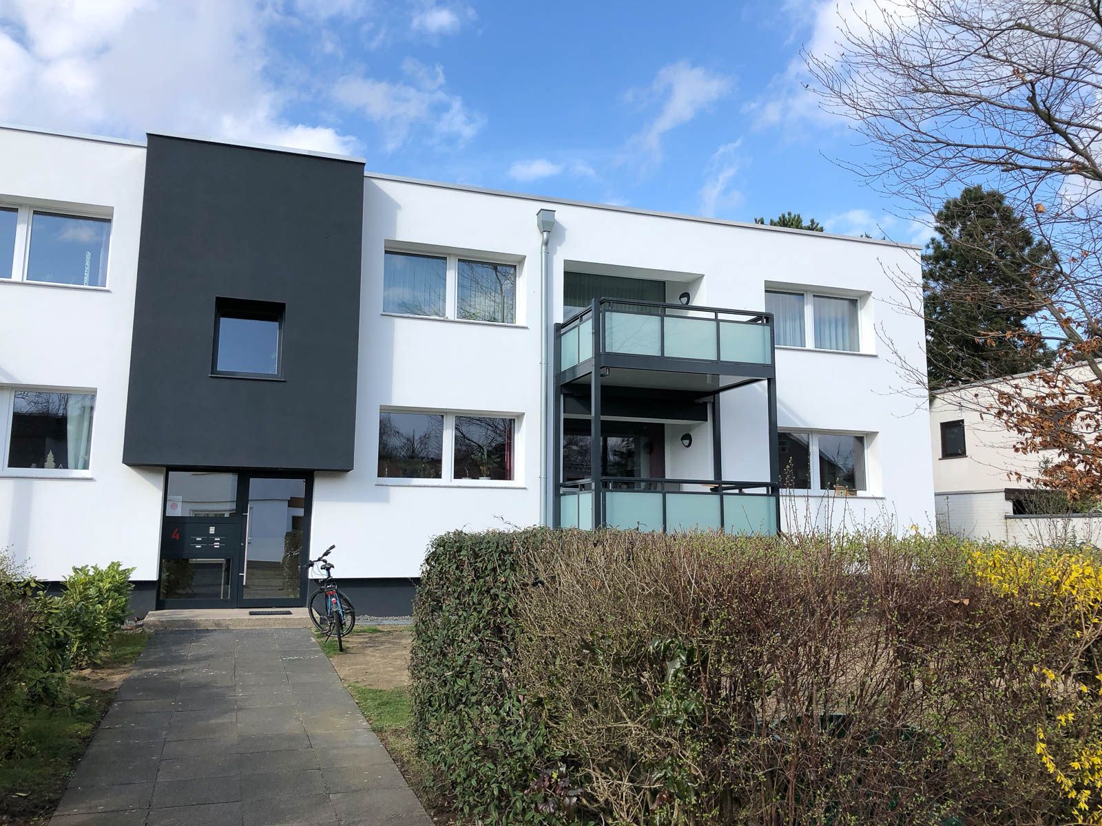 Ein weißes Gebäude mit einem Balkon und einem davor geparkten Fahrrad