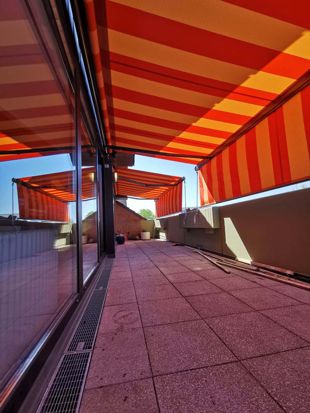 Eine rot-gelb gestreifte Markise bedeckt einen gemauerten Gehweg.