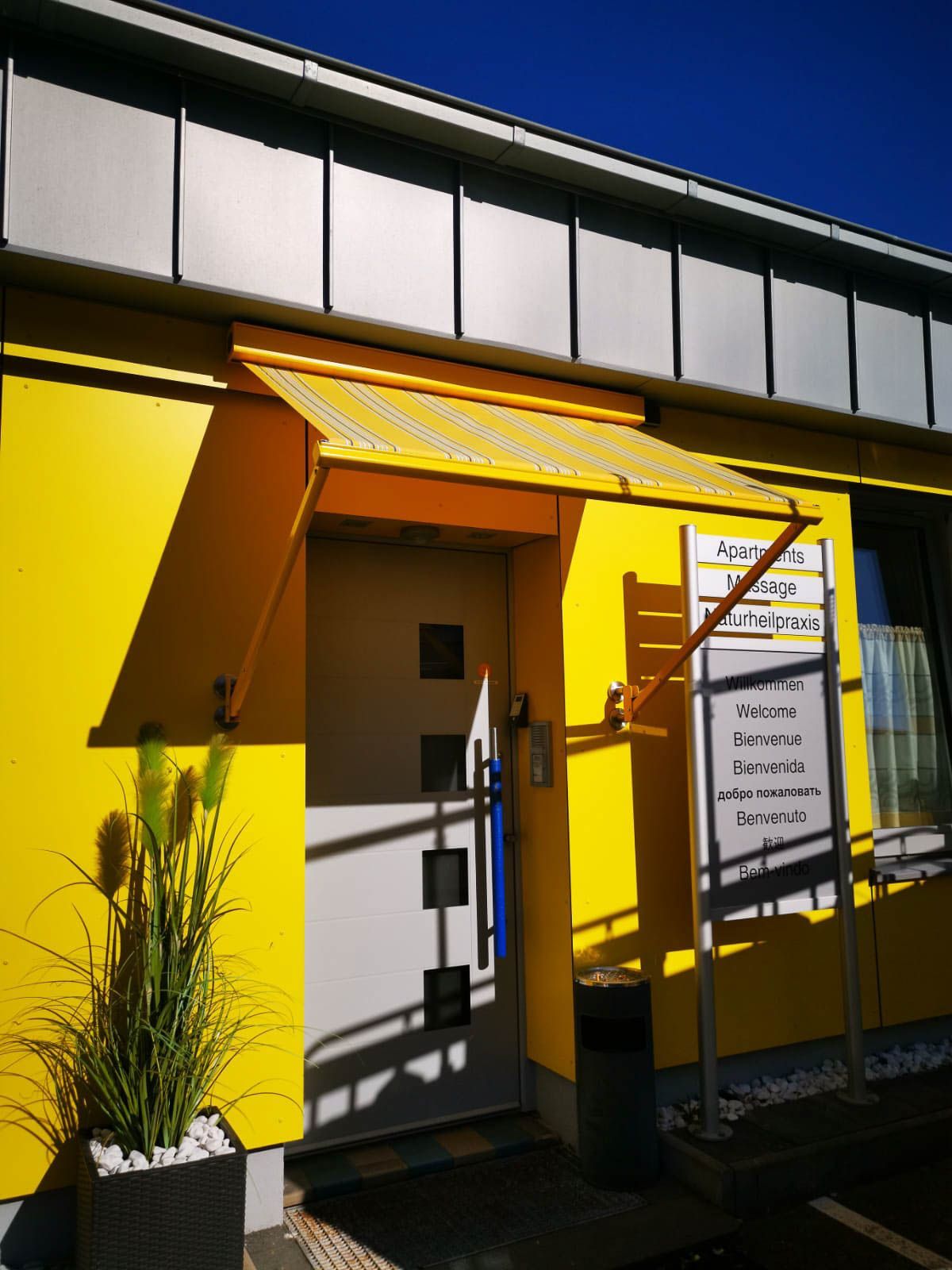 Ein gelbes Gebäude mit einem Vordach über der Tür