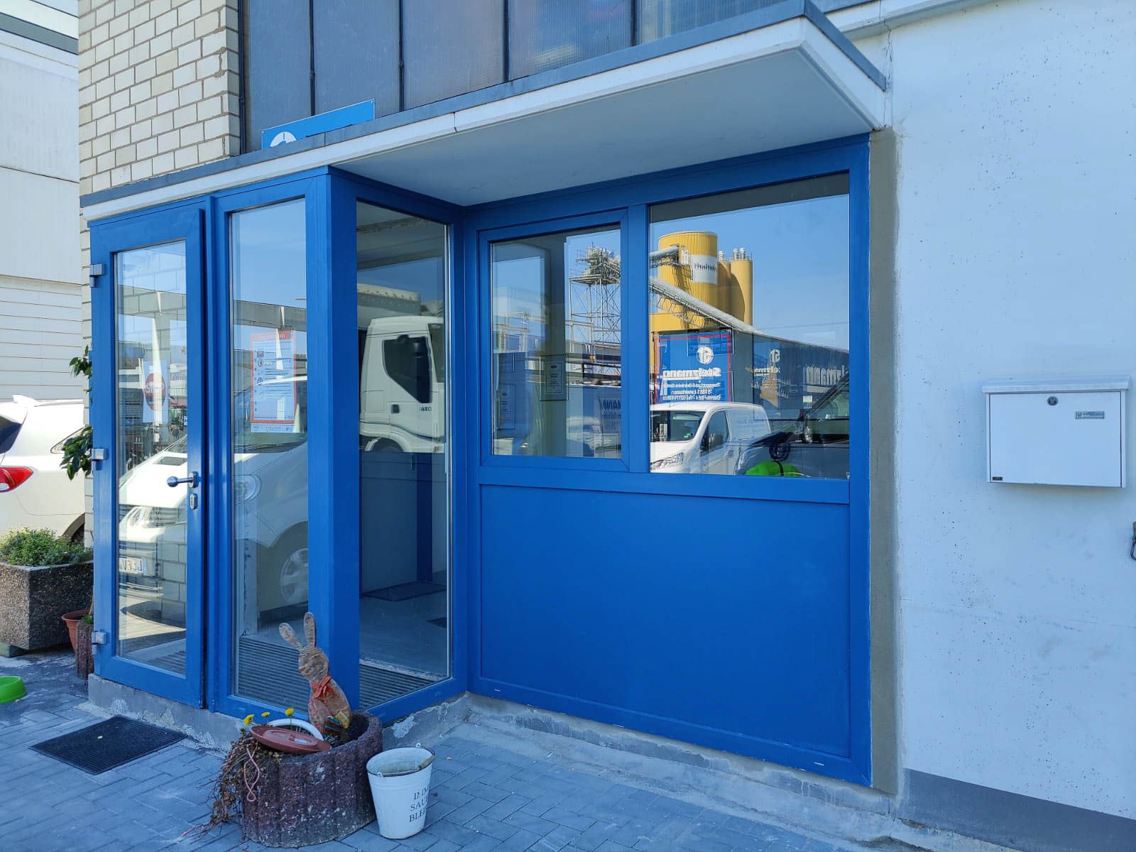 An der Seite eines Gebäudes befindet sich eine blaue Tür mit vielen Fenstern.