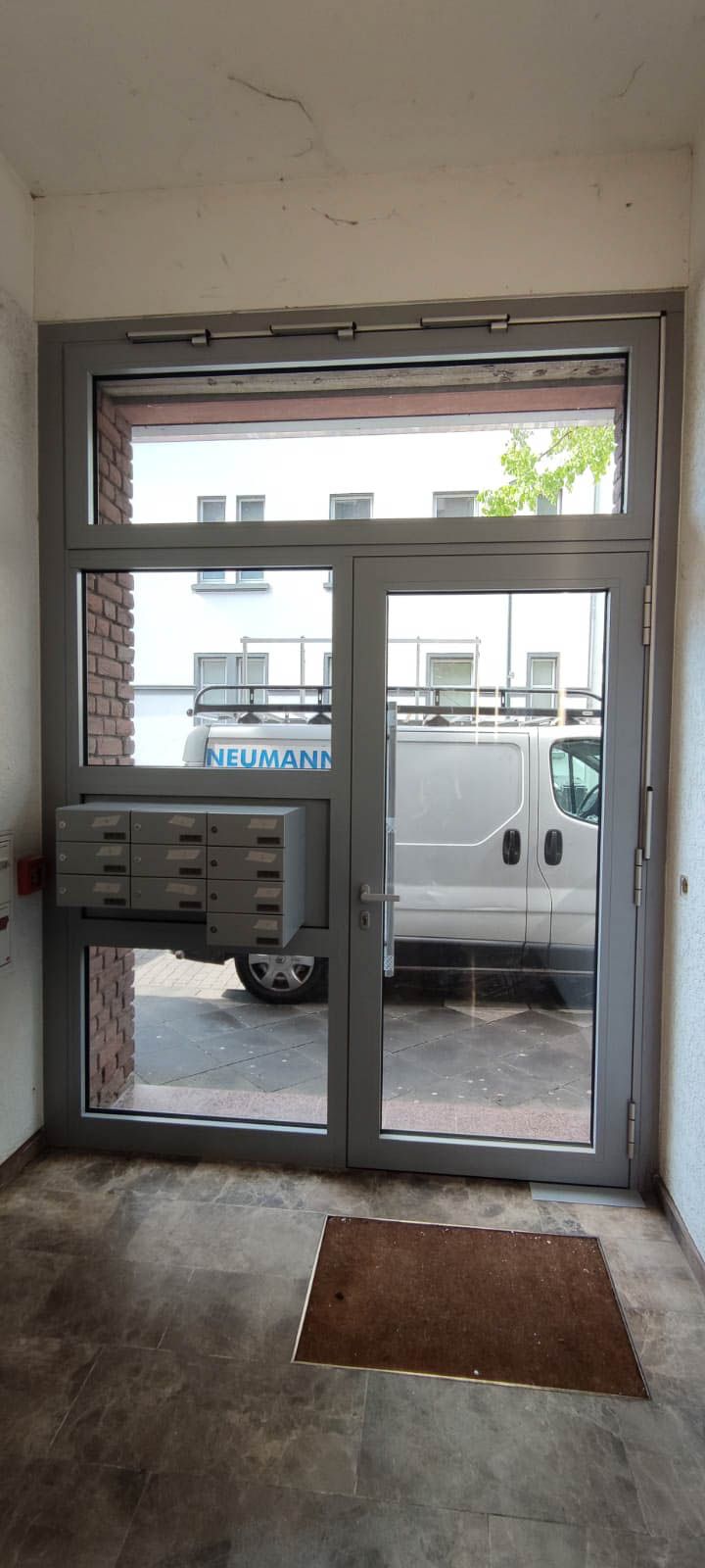 Vor der Tür eines Gebäudes parkt ein weißer Lieferwagen.