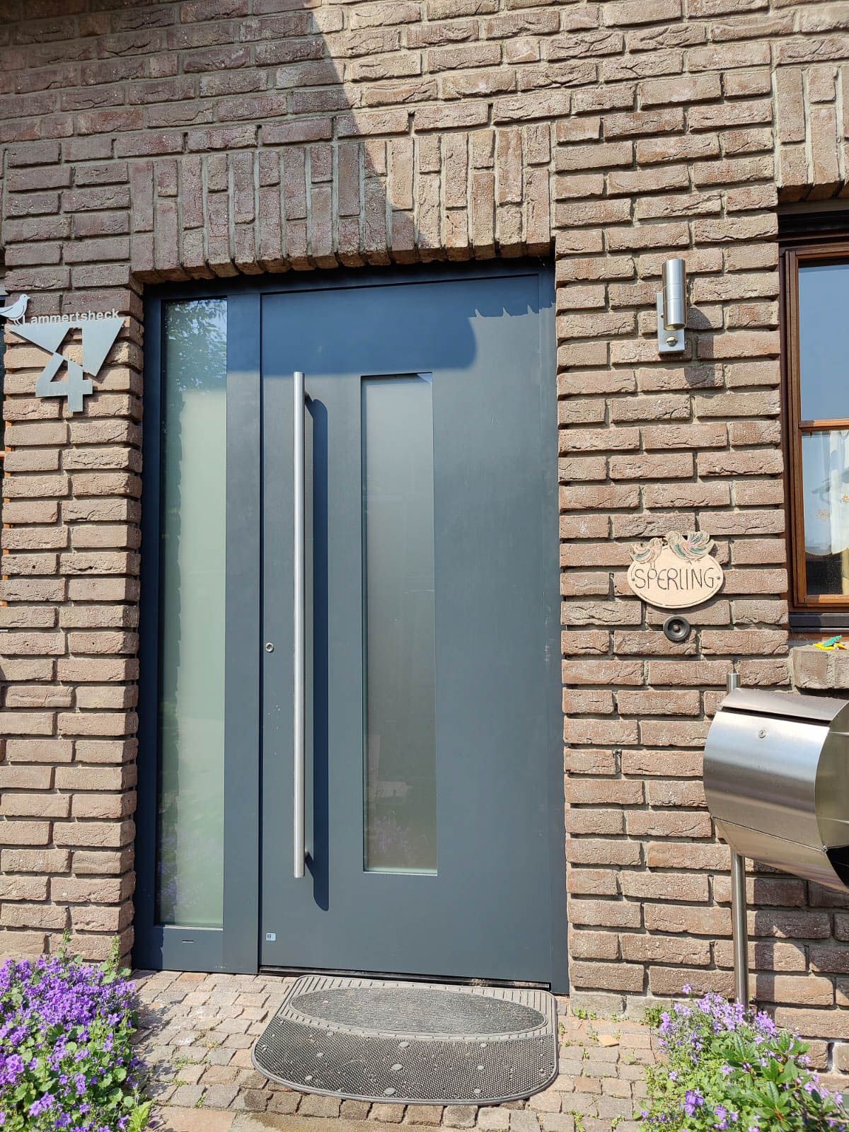 Ein Backsteingebäude mit einer grauen Tür und einem Briefkasten davor.