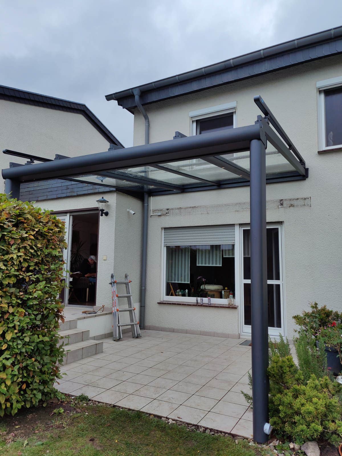 Ein weißes Haus mit einer glasüberdachten Terrasse davor