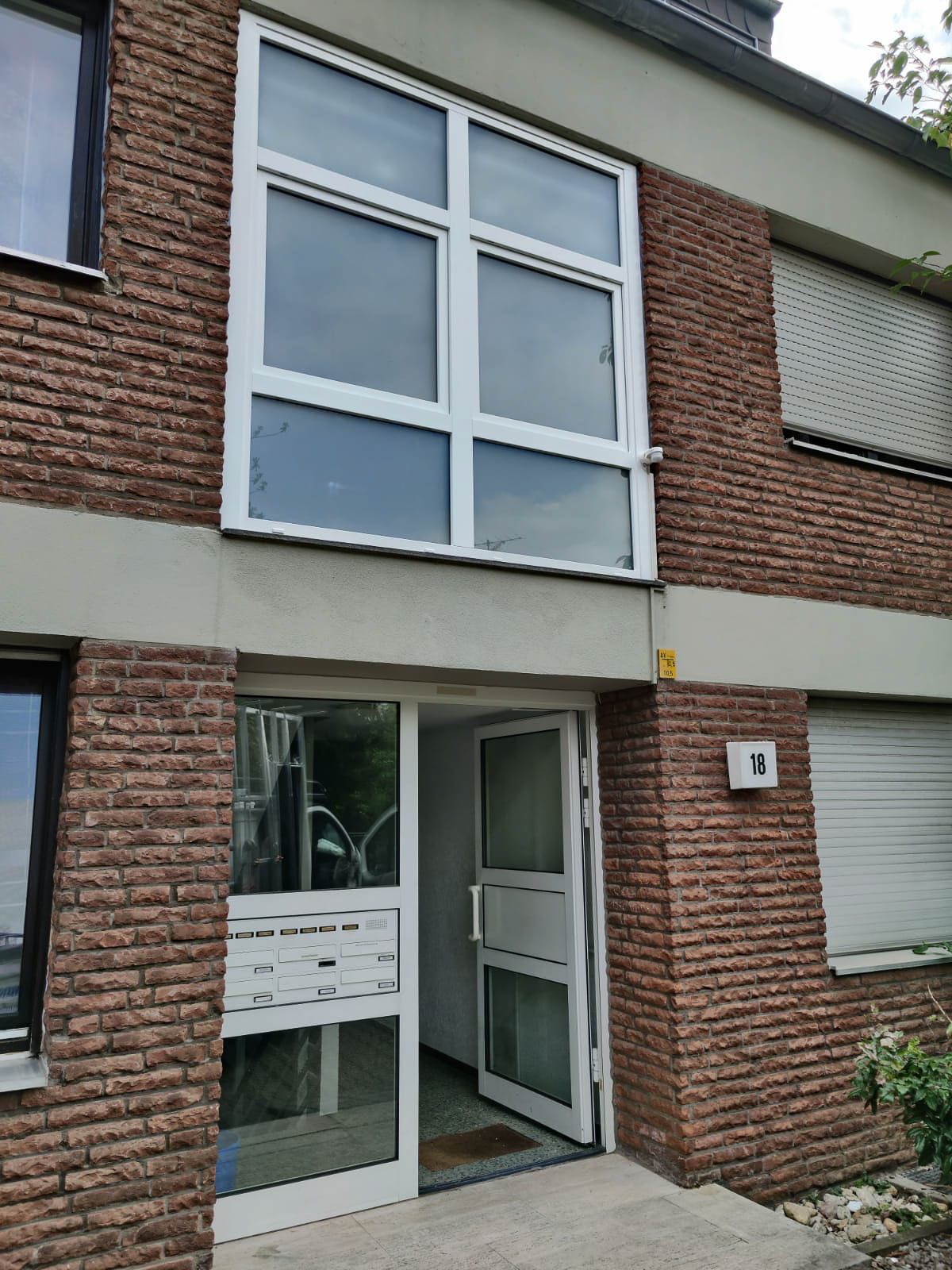 Ein Backsteingebäude mit einer weißen Tür und Fenstern