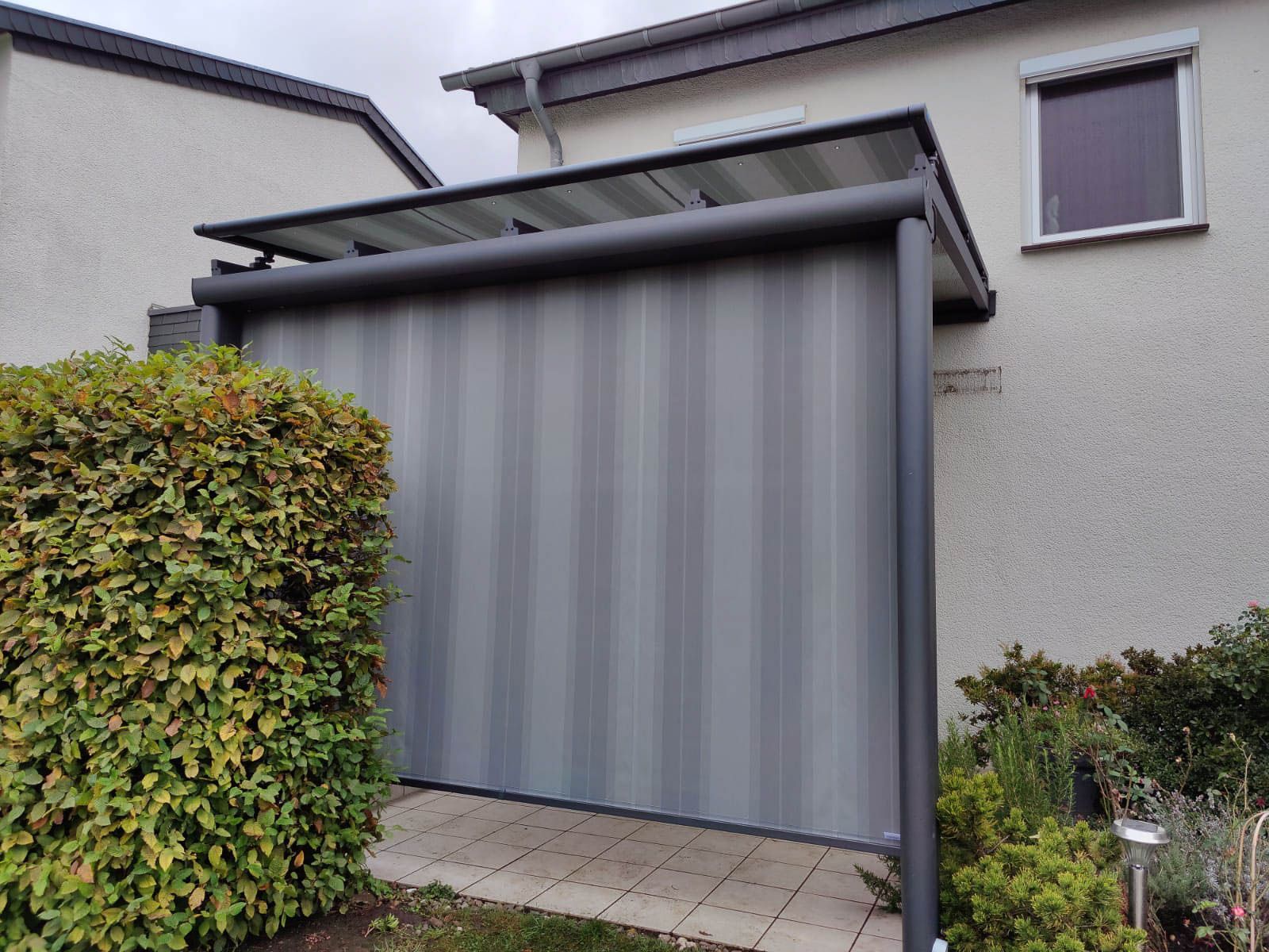 Vor einem Haus steht ein graues Garagentor.