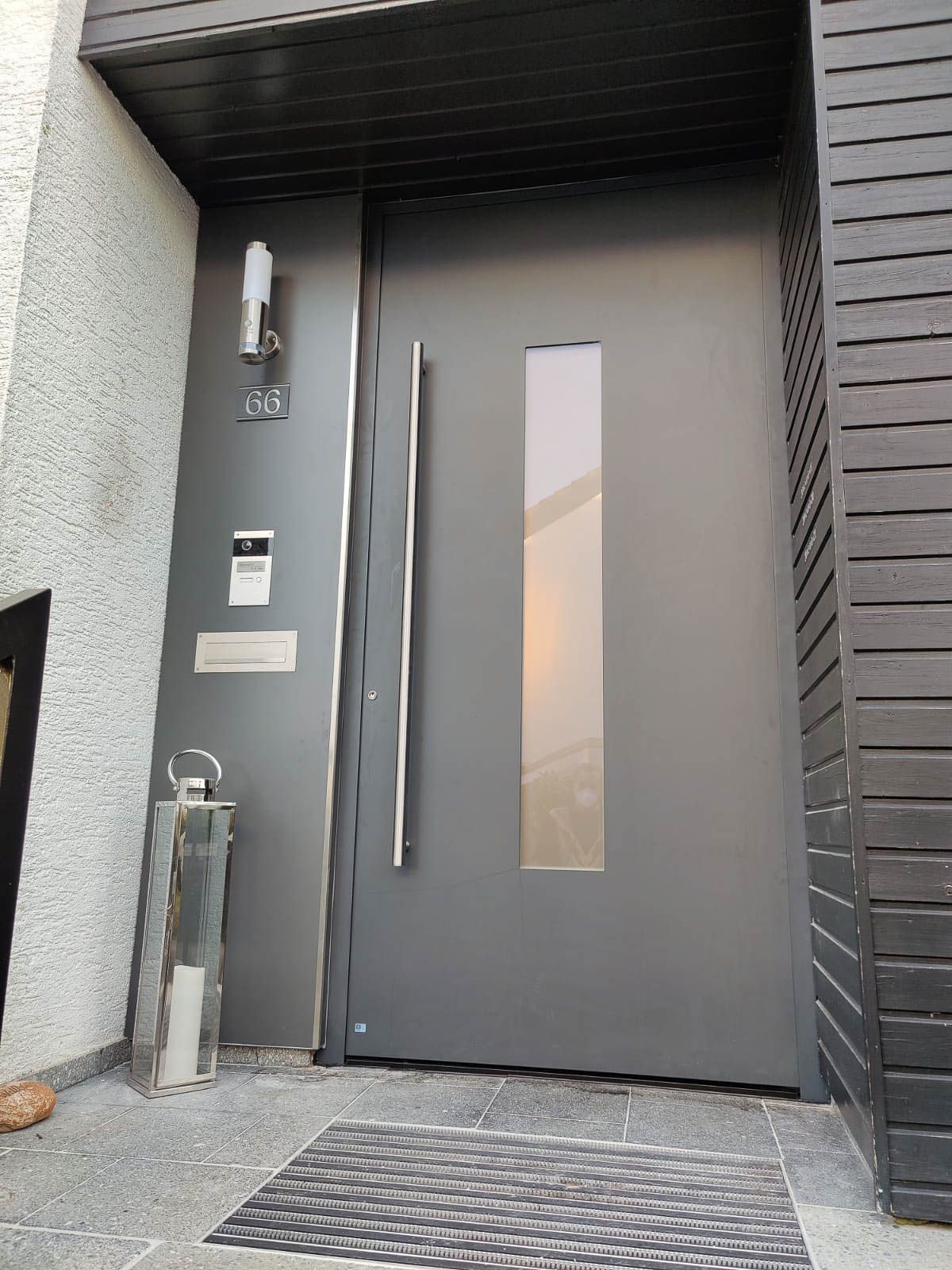 Eine graue Tür mit einem Glasfenster und einem Edelstahlgriff