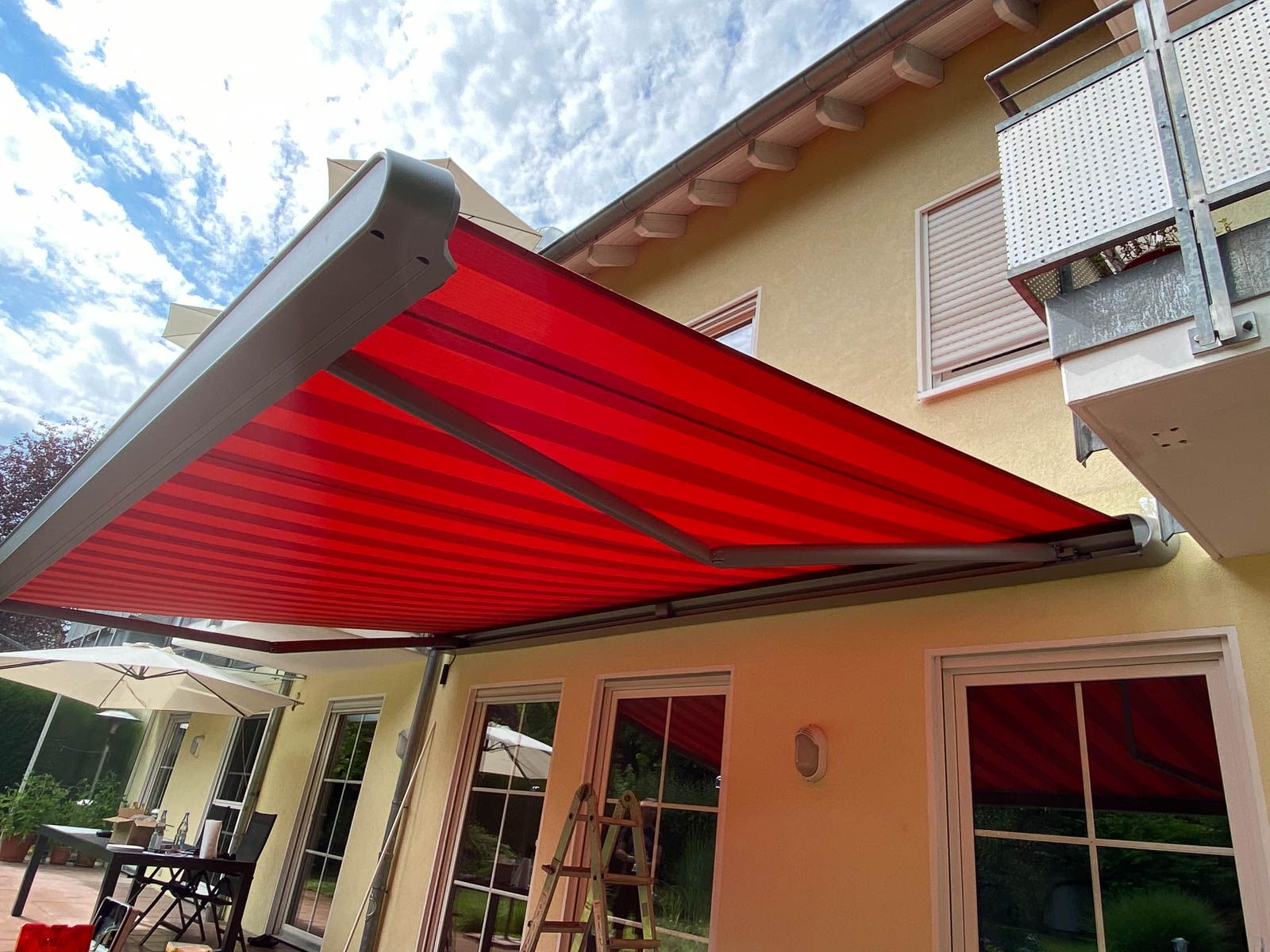 An der Seite eines Hauses ist eine rote Markise.