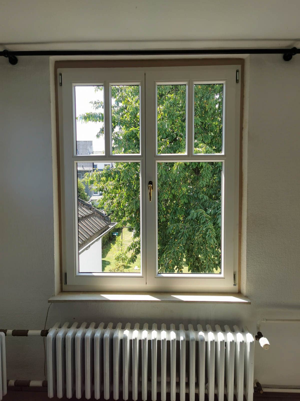 Ein Zimmer mit Heizkörper und Fenster mit Blick auf Bäume