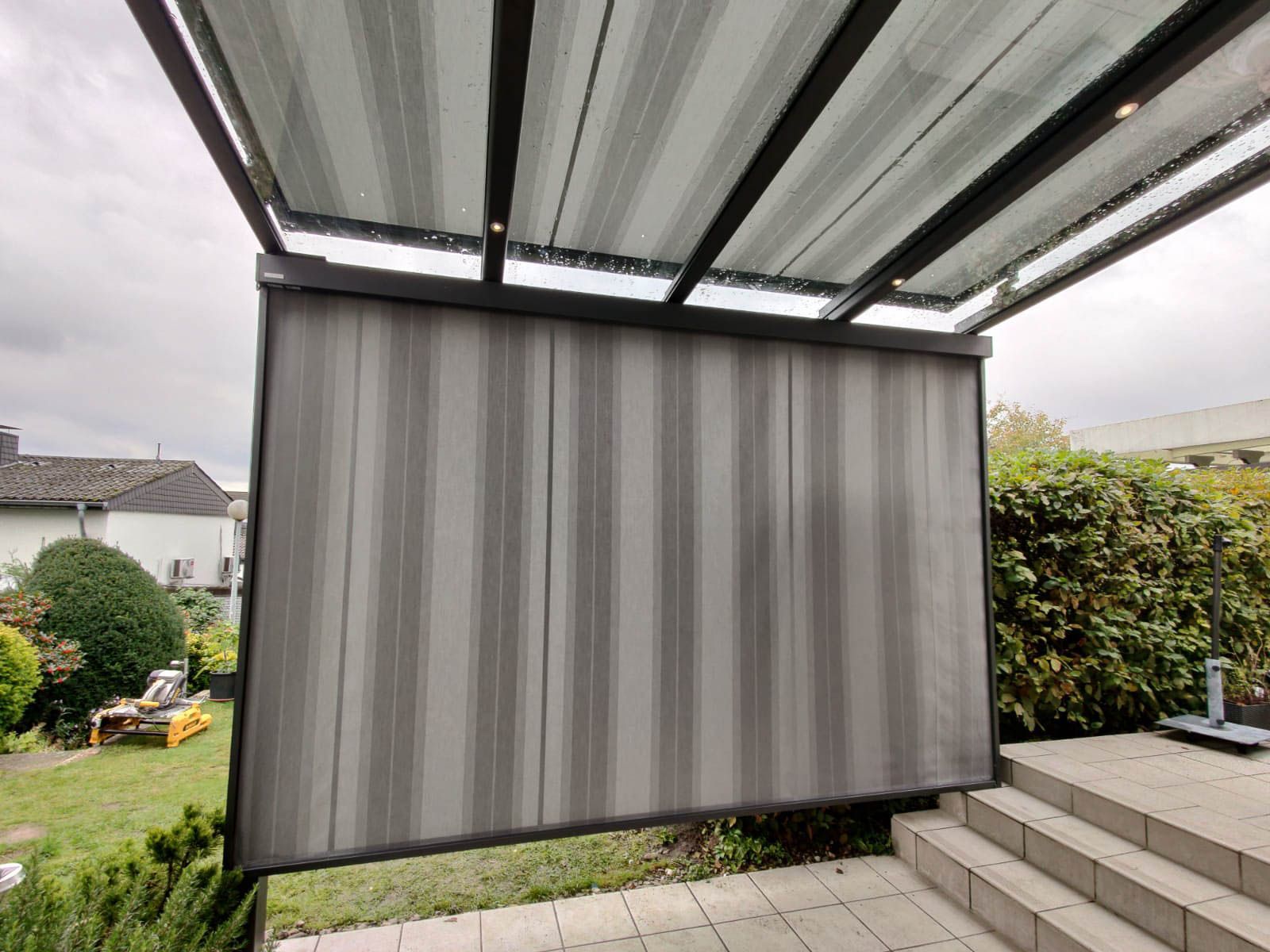 An der Seite einer Terrasse hängt ein grauer Vorhang.