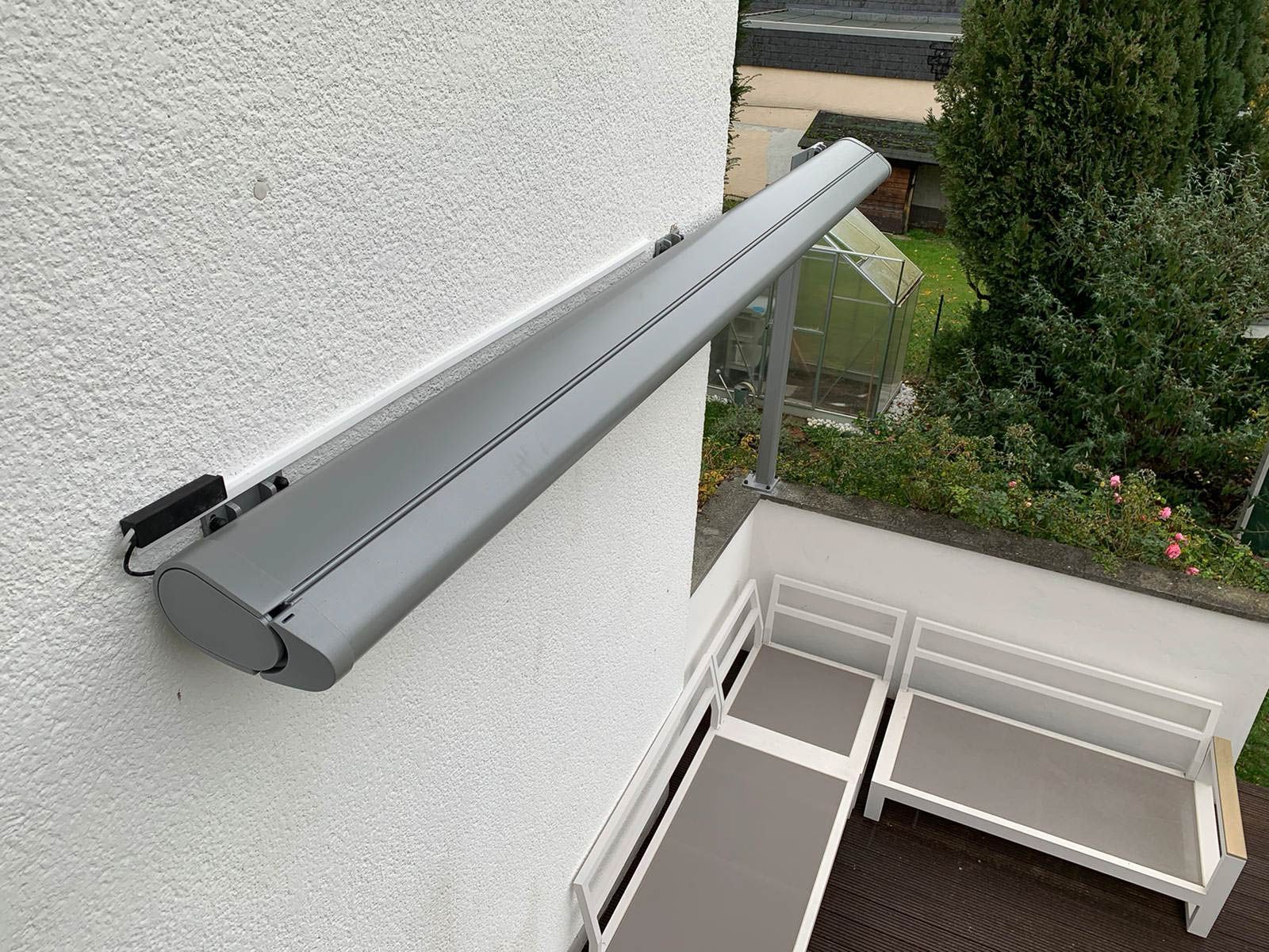 An der Seite eines Gebäudes ist eine graue Markise angebracht.