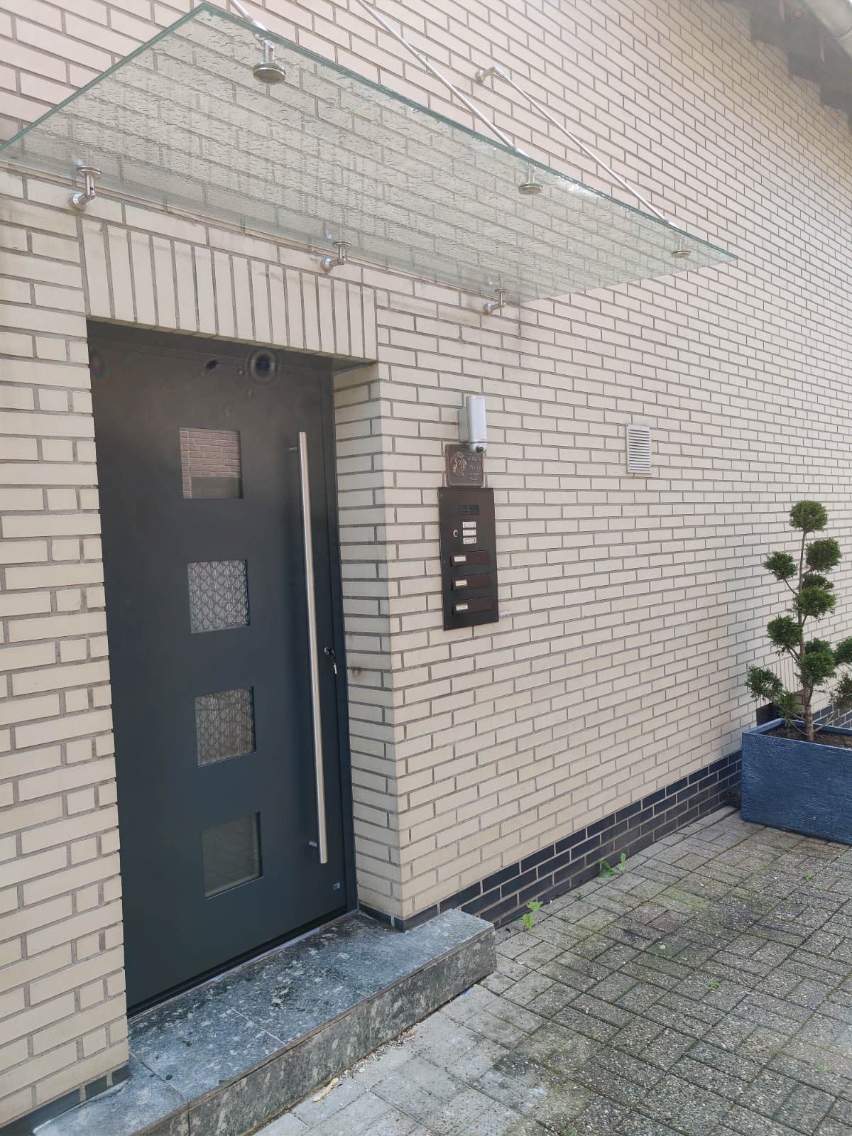 Ein Backsteingebäude mit einer schwarzen Tür und einem Glasdach darüber.