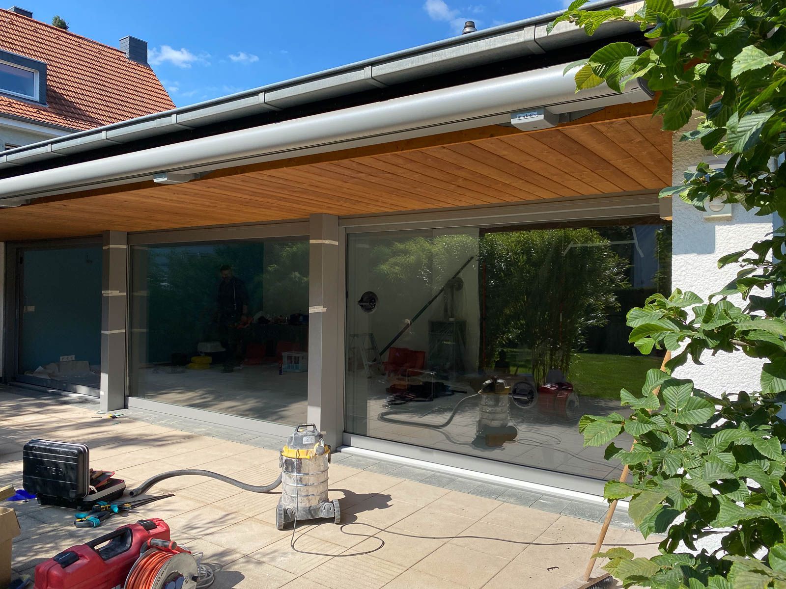 Auf einer Terrasse vor einem Haus steht ein Staubsauger.