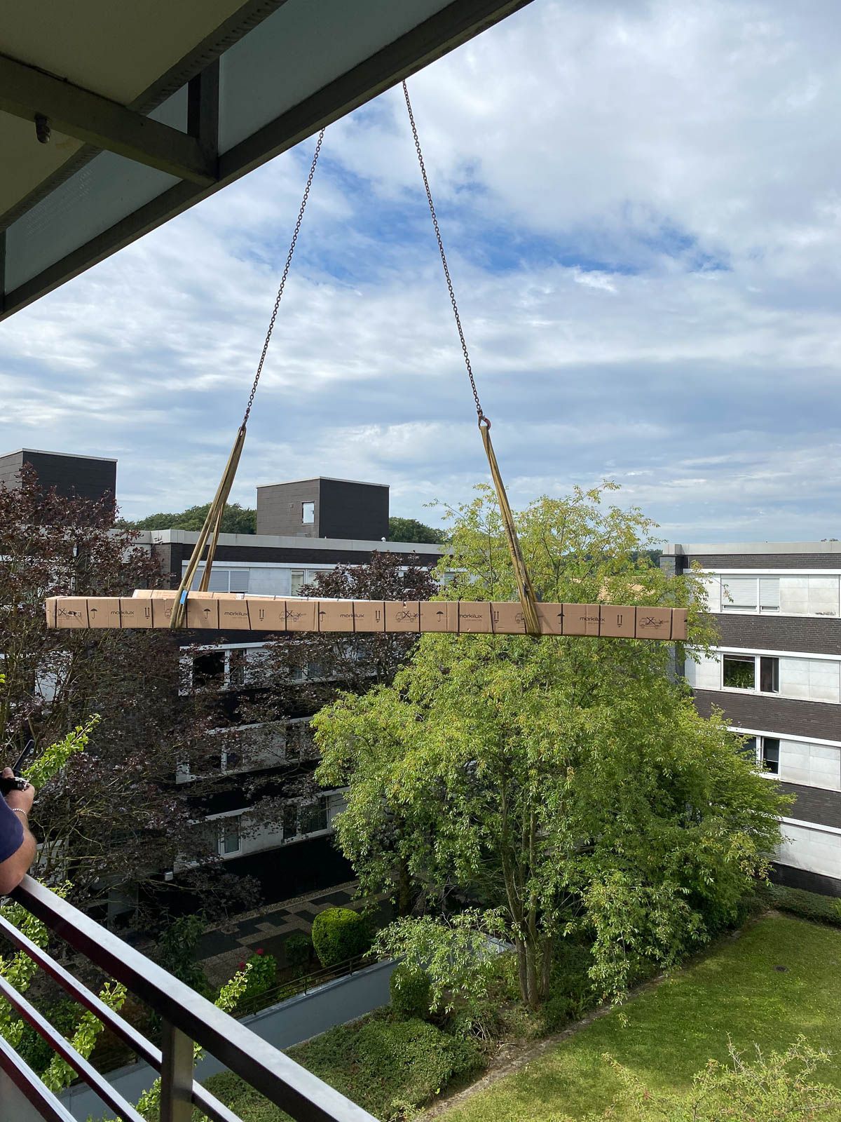 Ein großes Stück Holz hängt an einem Kran auf einem Balkon