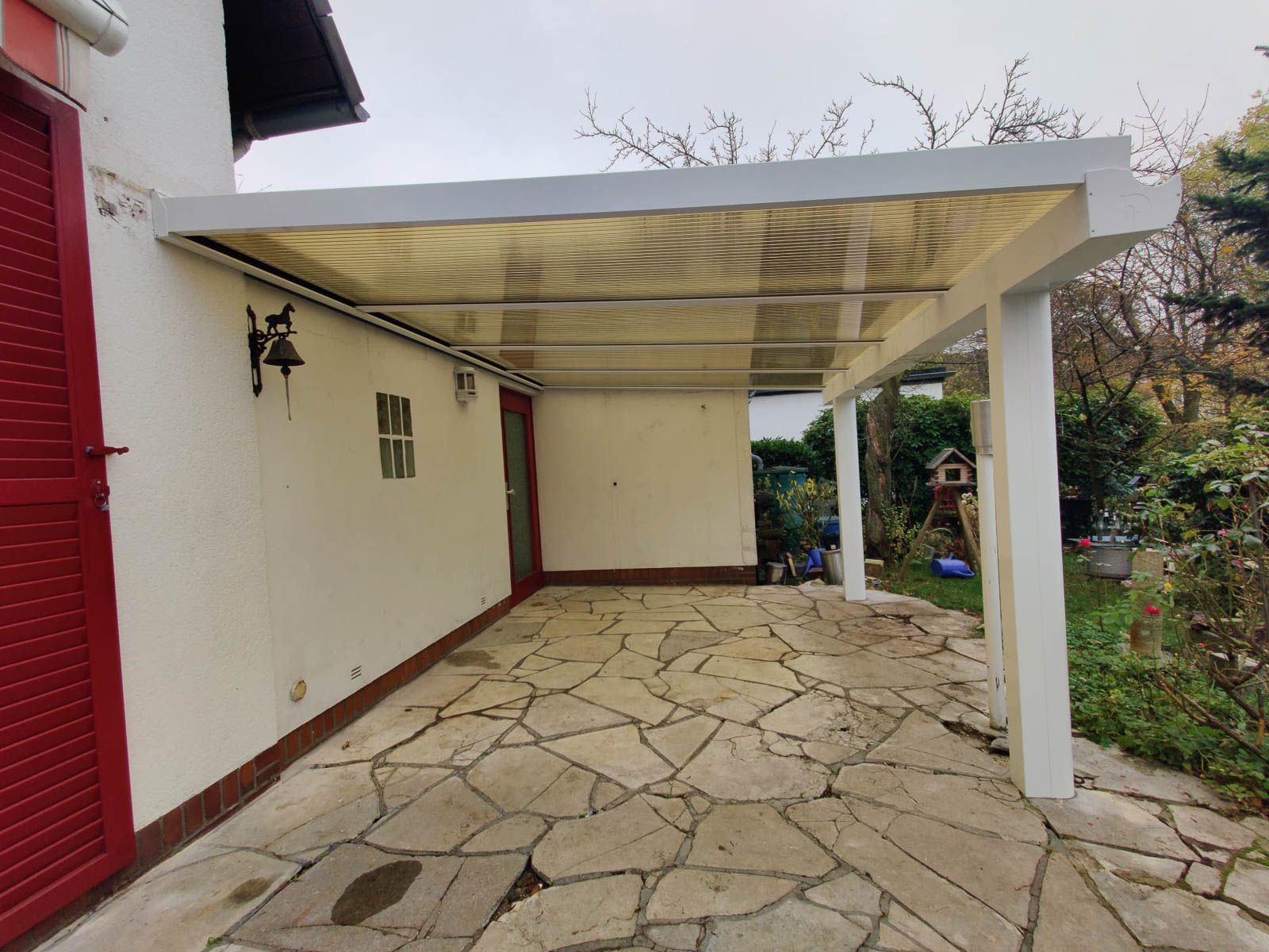 Ein weißes Haus mit einer roten Tür und einem Steinweg