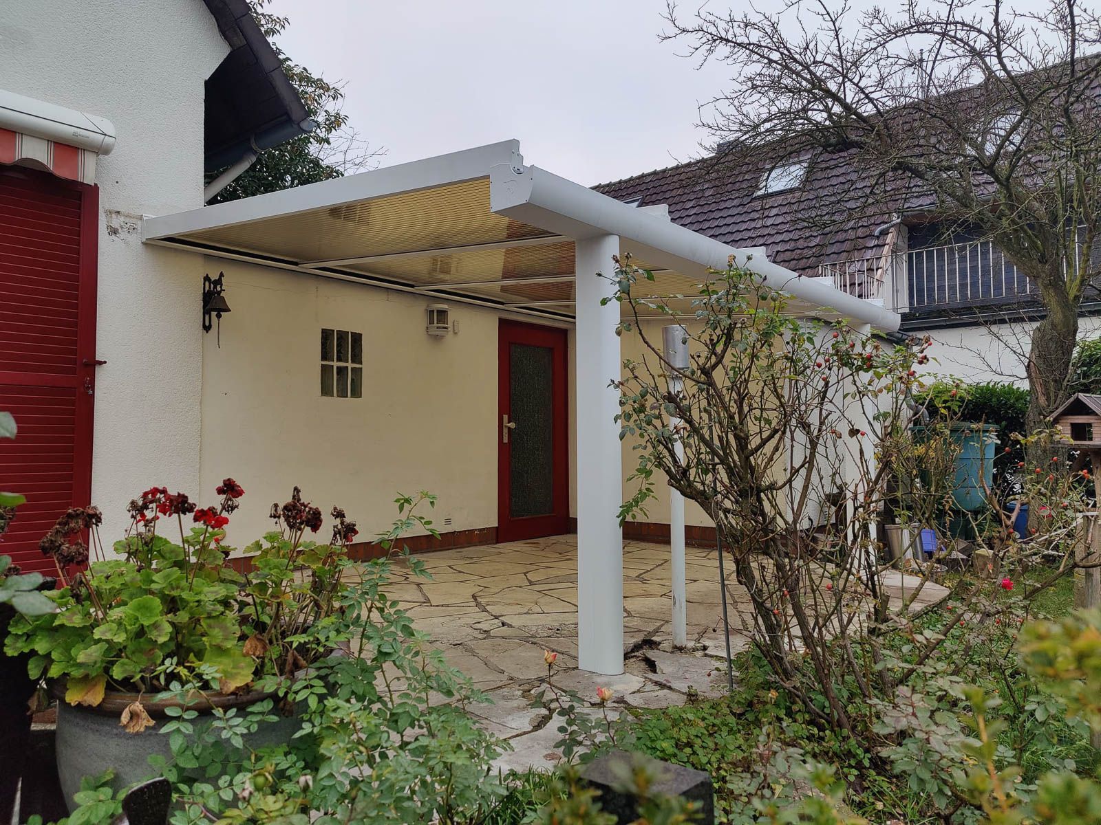 Vor einem Haus steht eine weiße Pergola.