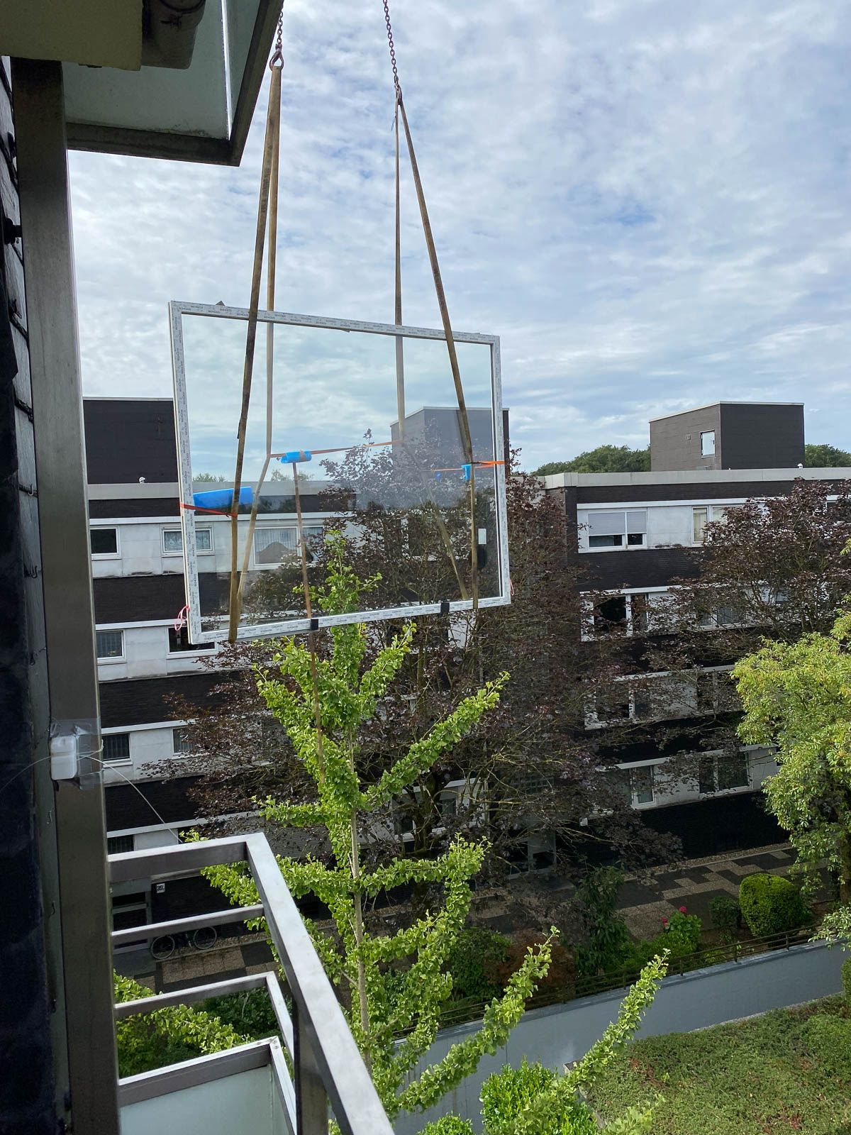 Ein Fenster wird mit einem Kran auf einen Balkon gehoben.