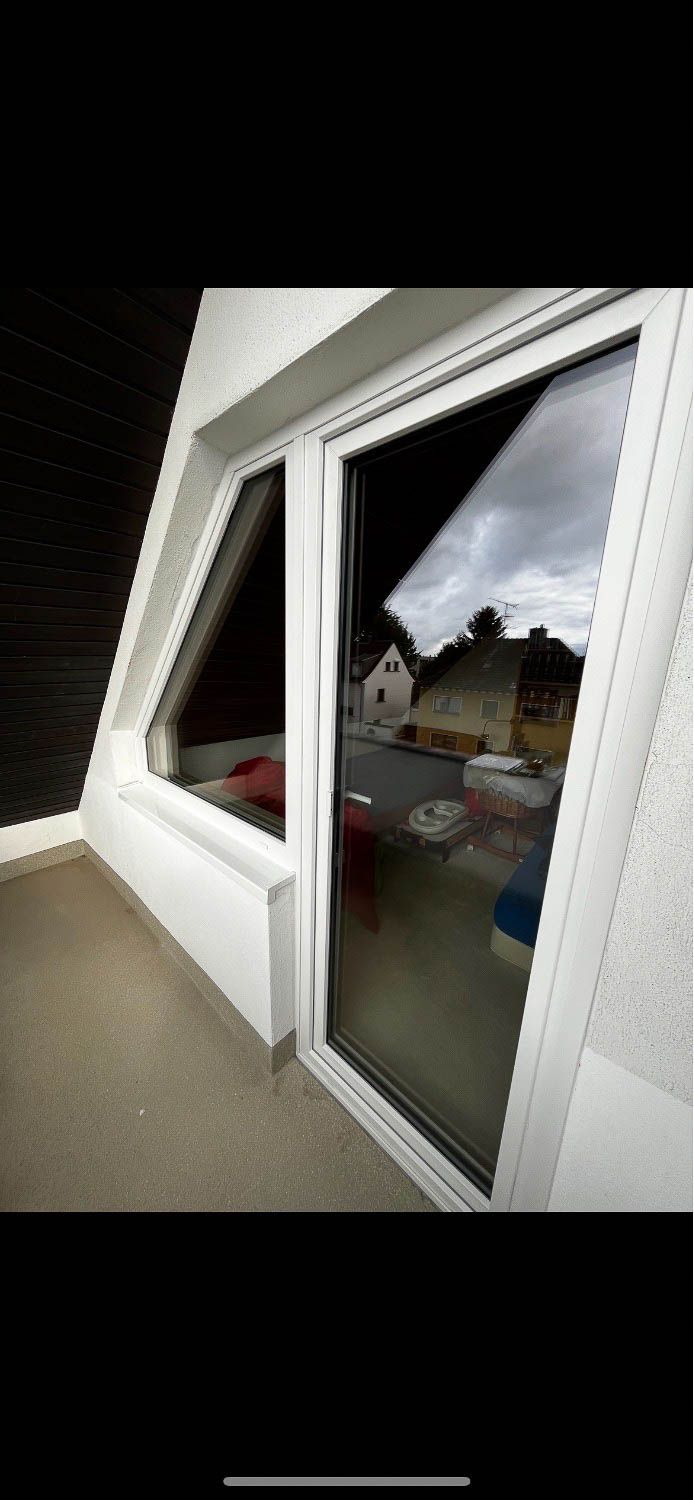 Ein Balkon mit einer Glasschiebetür und einem Fenster.