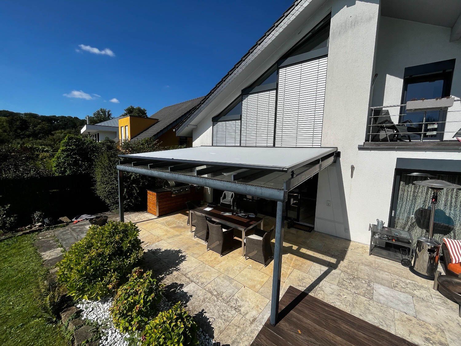 Ein Haus mit einer überdachten Terrasse und einem Tisch und Stühlen darunter.