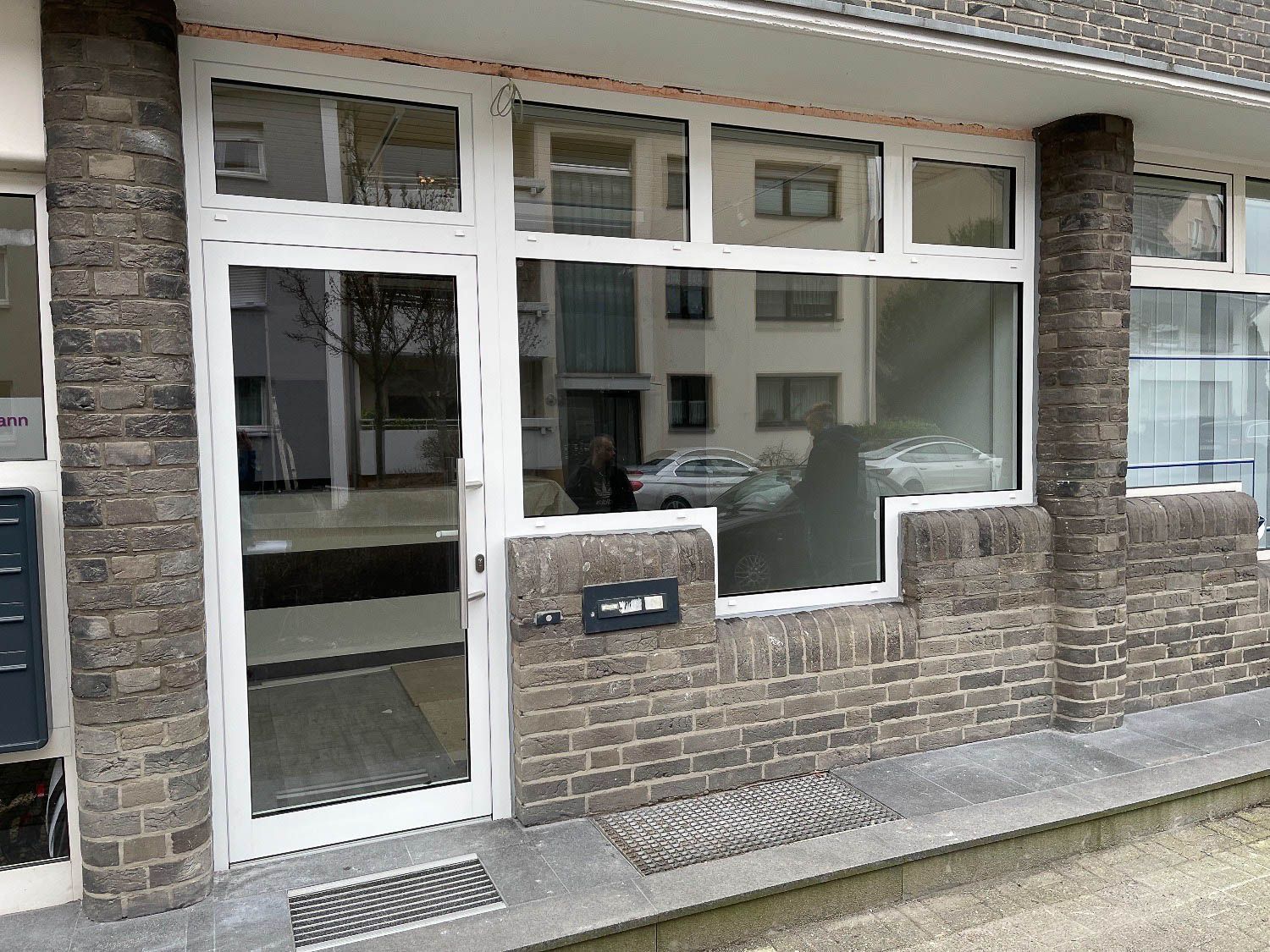 Ein Backsteingebäude mit einer weißen Tür und einem Fenster.