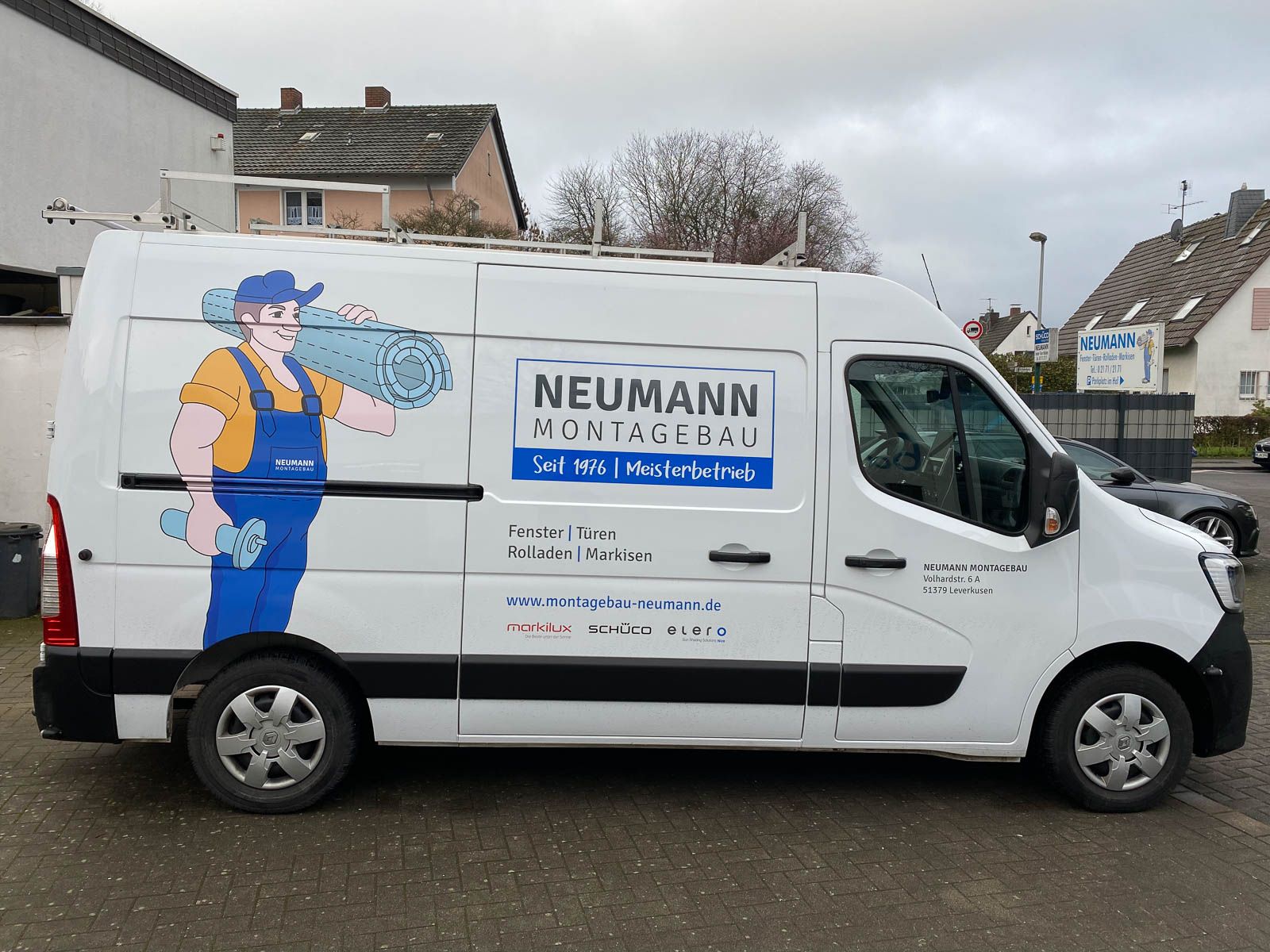 Ein weißer Neumann-Van steht auf einem Parkplatz