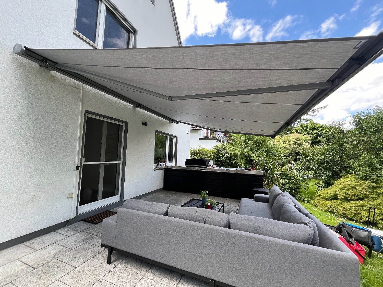 Eine Terrasse mit einer Couch und einem Tisch unter einer Markise.