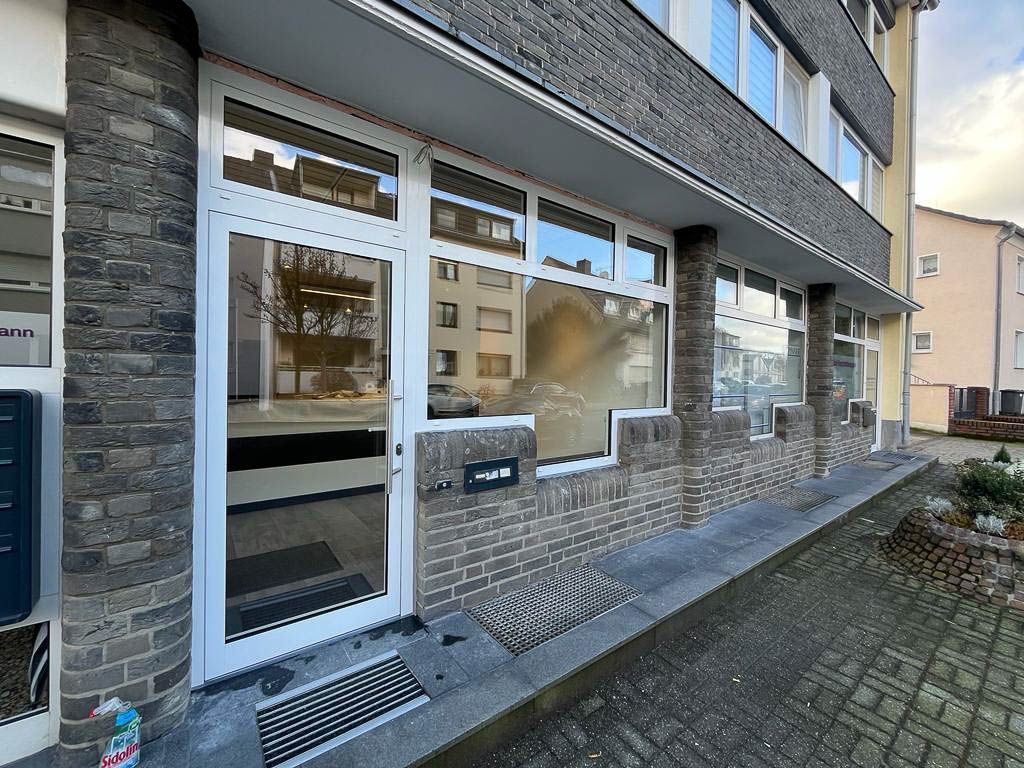 Ein Backsteingebäude mit einer weißen Tür und vielen Fenstern.