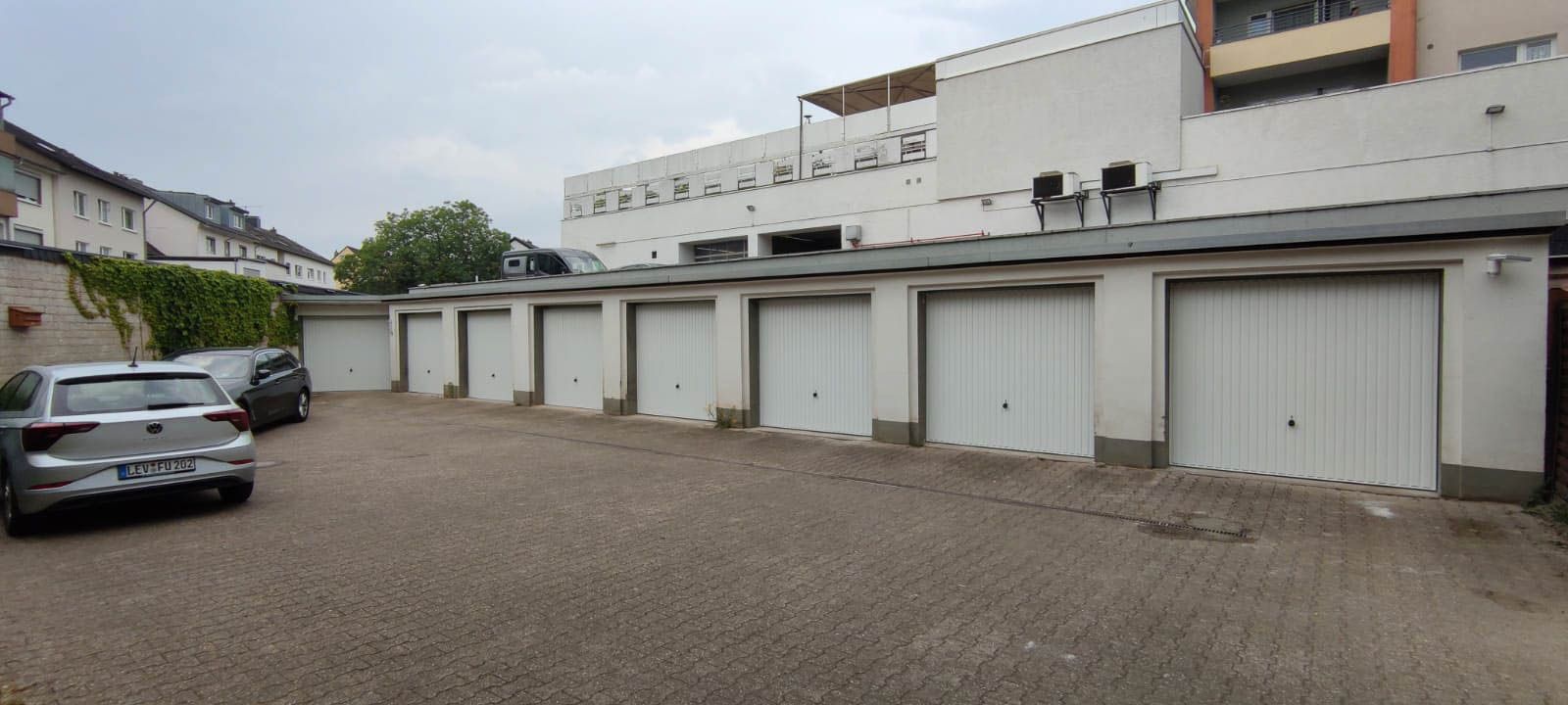 Eine Reihe von Garagen, vor denen Autos geparkt sind.