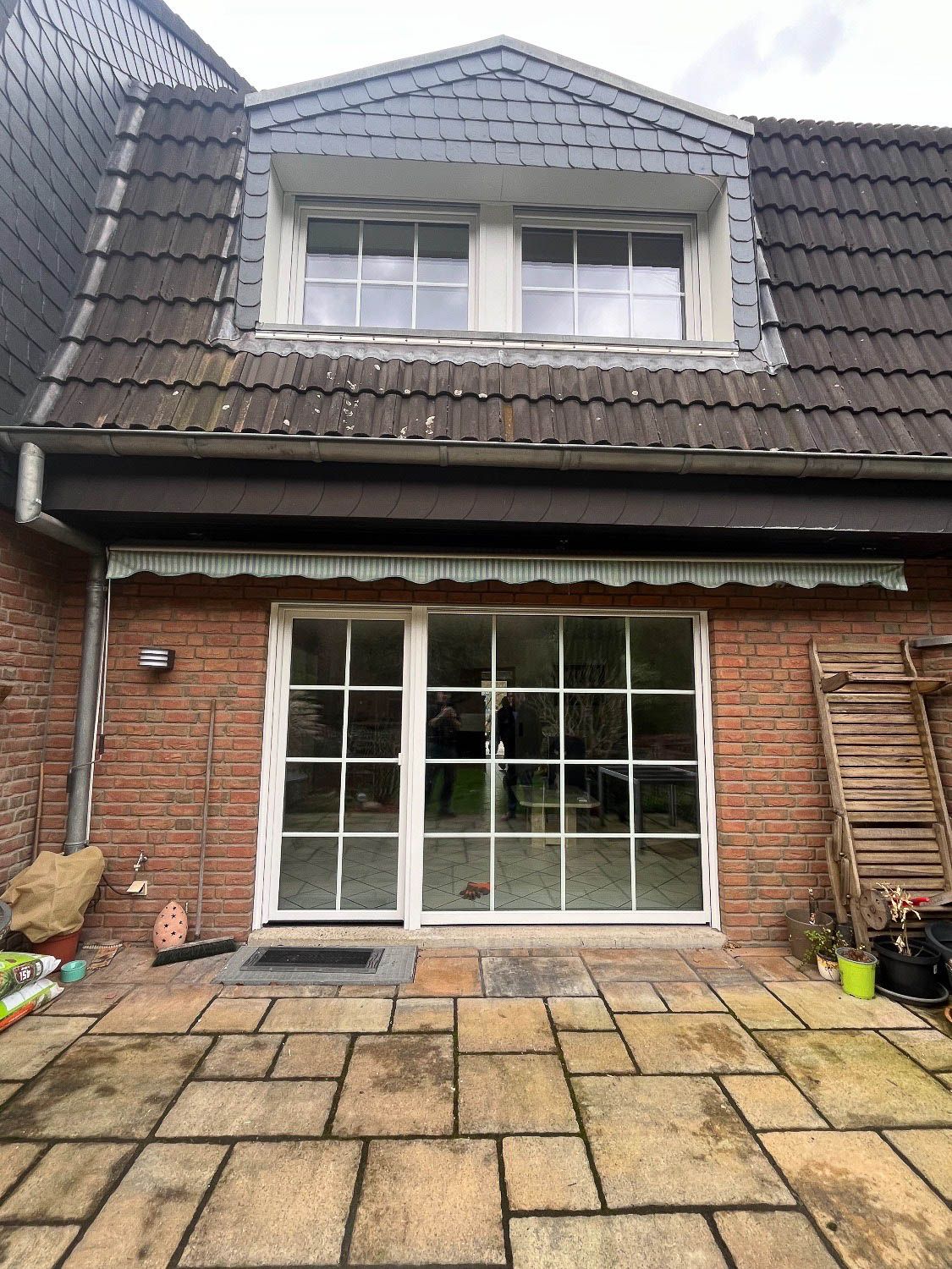 Die Rückseite eines Backsteinhauses mit einer Terrasse davor.