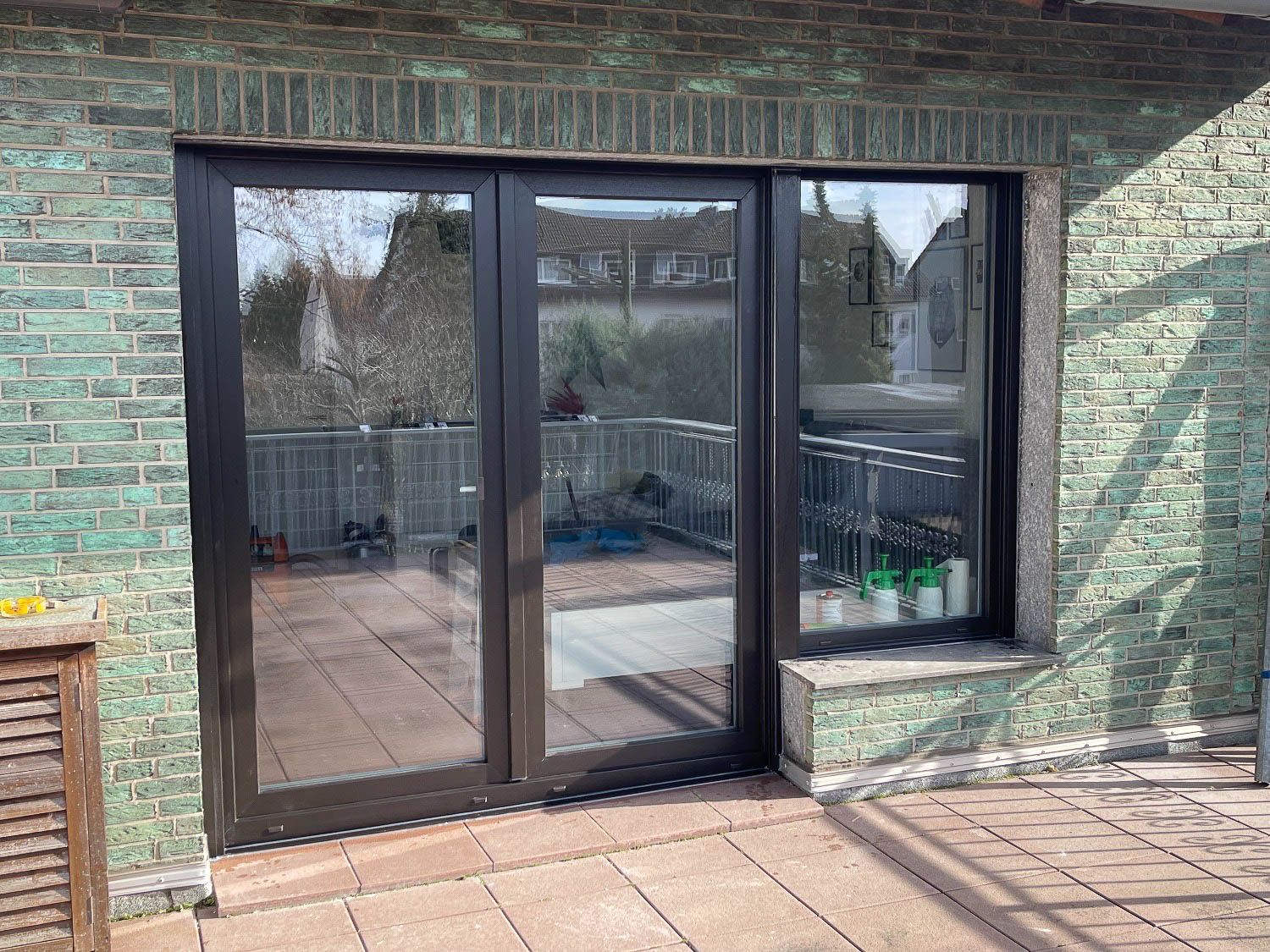 Ein Backsteingebäude mit Glasschiebetüren, die auf eine Terrasse führen.