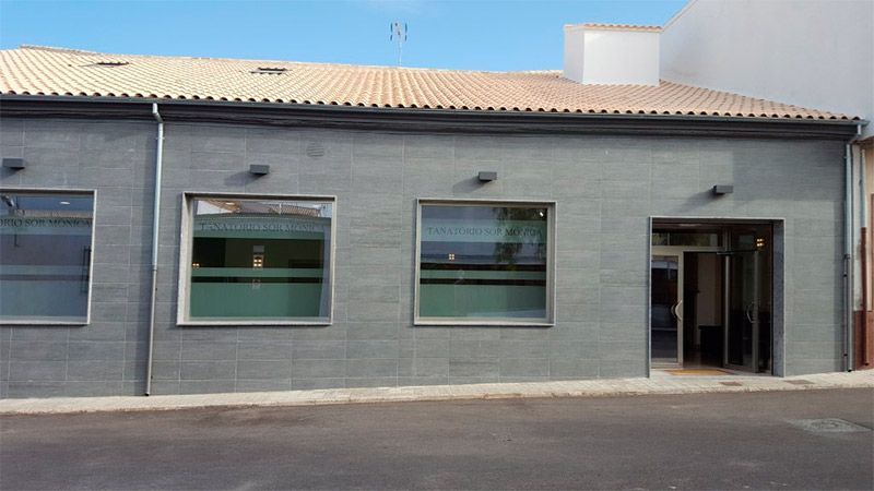 Un edificio gris con un techo marrón y muchas ventanas.