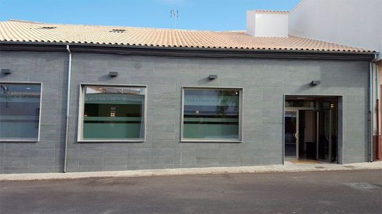 Un edificio gris con un techo marrón y muchas ventanas.