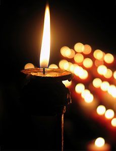 Un primer plano de una vela encendida en una habitación oscura.