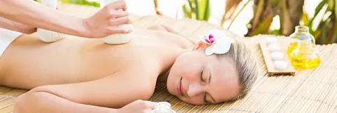 Una mujer está recibiendo un masaje en un spa con una flor en el pelo.