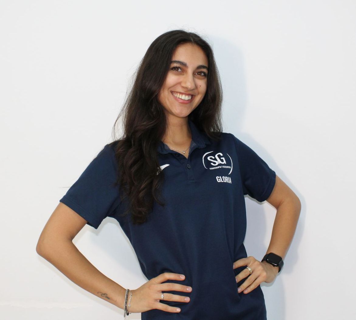 Mujer de cabello oscuro, vestida con un polo azul marino, sonriendo, con las manos en las caderas