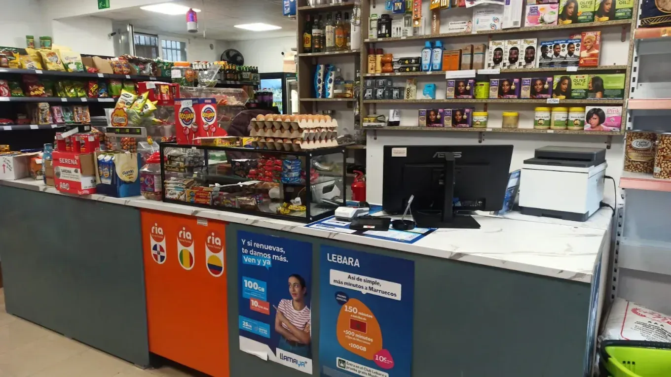 Mostrador de tienda de conveniencia con bocadillos, bebidas y caja registradora.