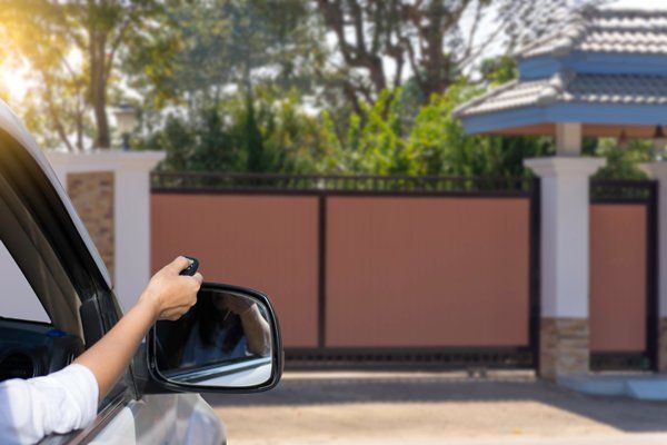 Une dame en train d'ouvrir un portail électrique