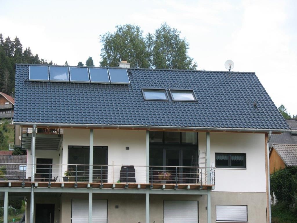 Modernes Haus mit dunkelgrauem Satteldach, Solarpanelen und mehreren Dachfenstern