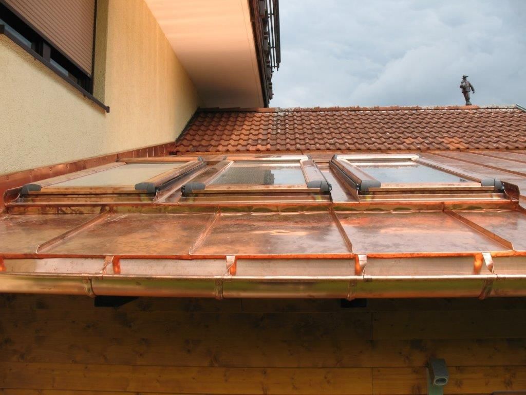 Detailansicht von Kupfer-Dachrinnen und Dachfenstern auf einem Ziegeldach