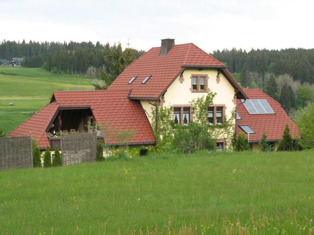 Großes gelbes Wohnhaus mit rotem Ziegeldach auf einer grünen Wiese