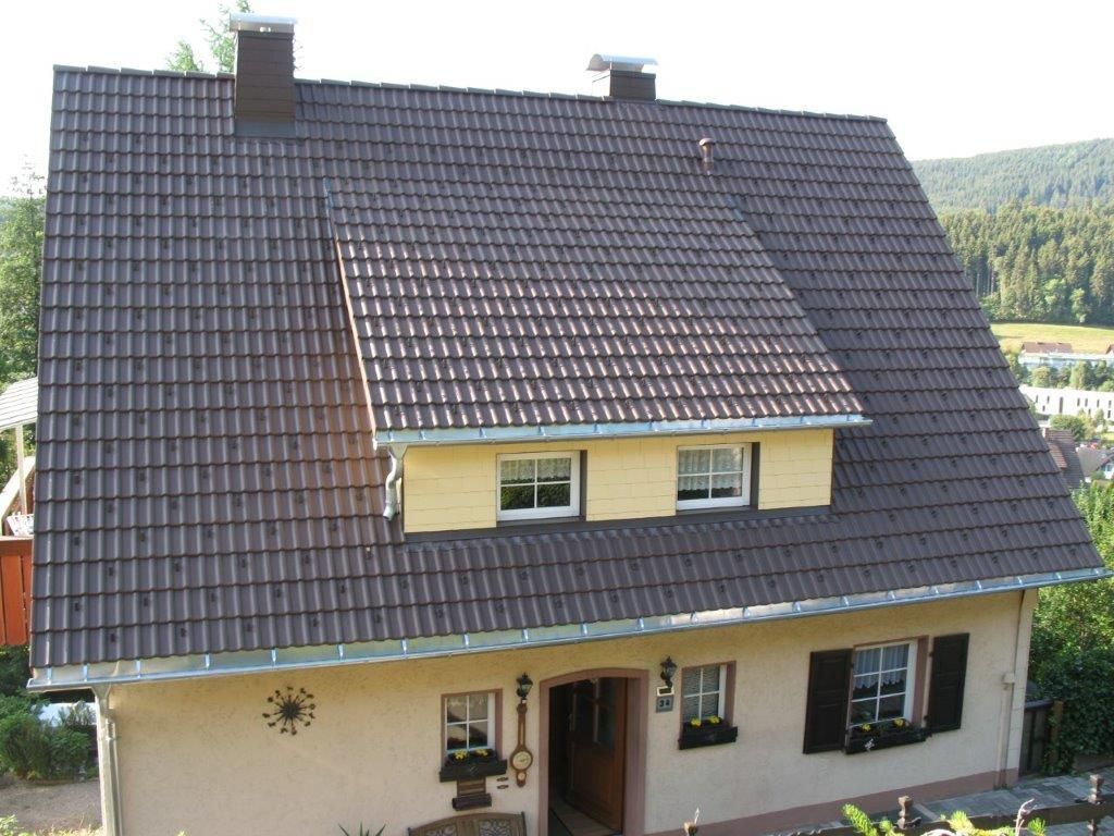 Dunkelgraues Steildach mit einer großen Gaube und mehreren Fenstern