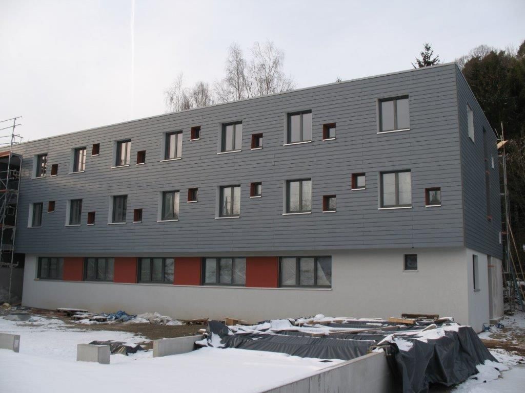 Fassade eines modernen dreistöckigen Gebäudes mit vielen kleinen Fenstern und einem Balkon