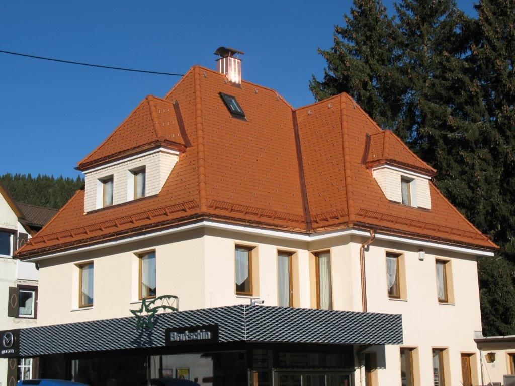 Ein renoviertes Gebäude mit Walmdach, roten Dachziegeln und Dachgauben
