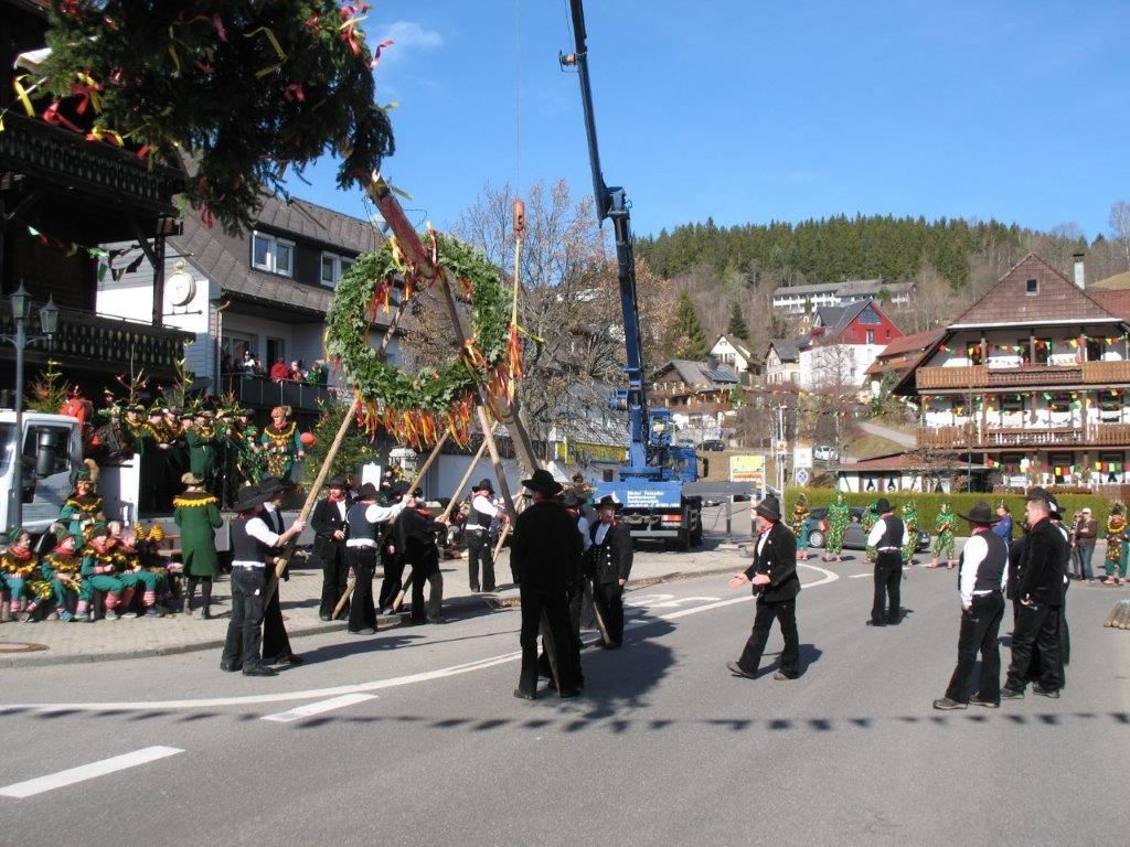 Musikkapelle marschiert bei einem Richtfest, im Hintergrund ein Richtkranz am Kran