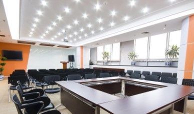 Una luminosa sala de conferencias con un gran escritorio cuadrado rodeado de sillas.