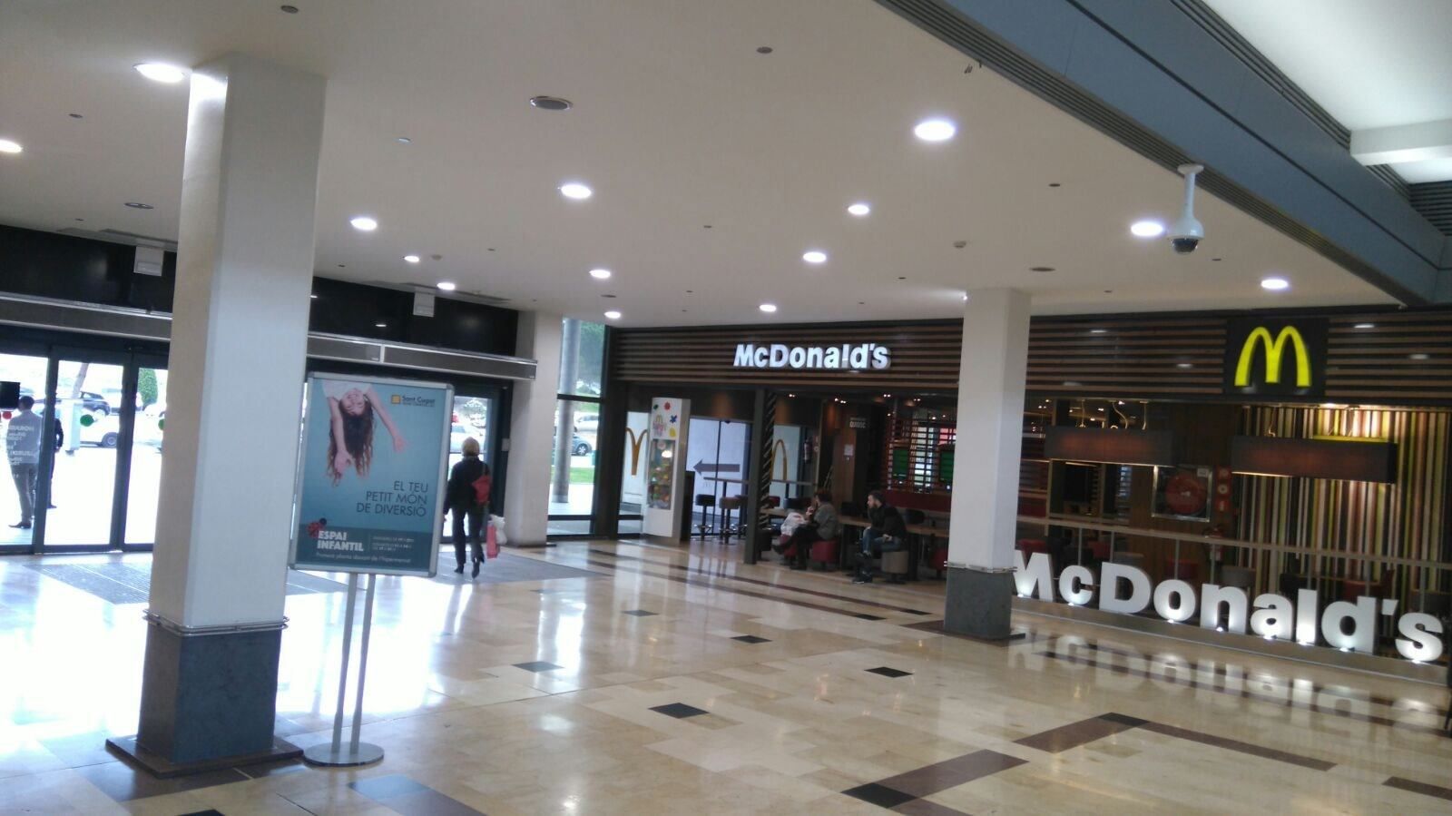La entrada de un restaurante McDonald's en un pasillo de un centro comercial cubierto de azulejos y muy bien iluminado.