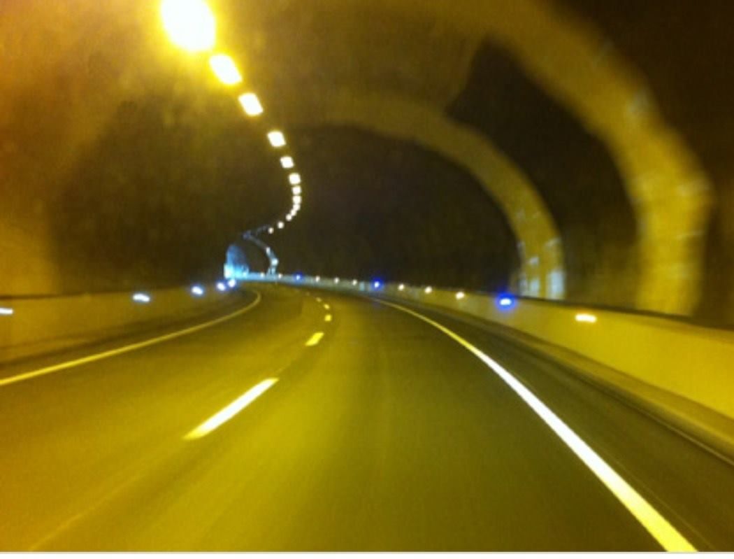 Vista borrosa desde un vehículo dentro de un túnel con luces amarillas en el techo y reflectores azules.