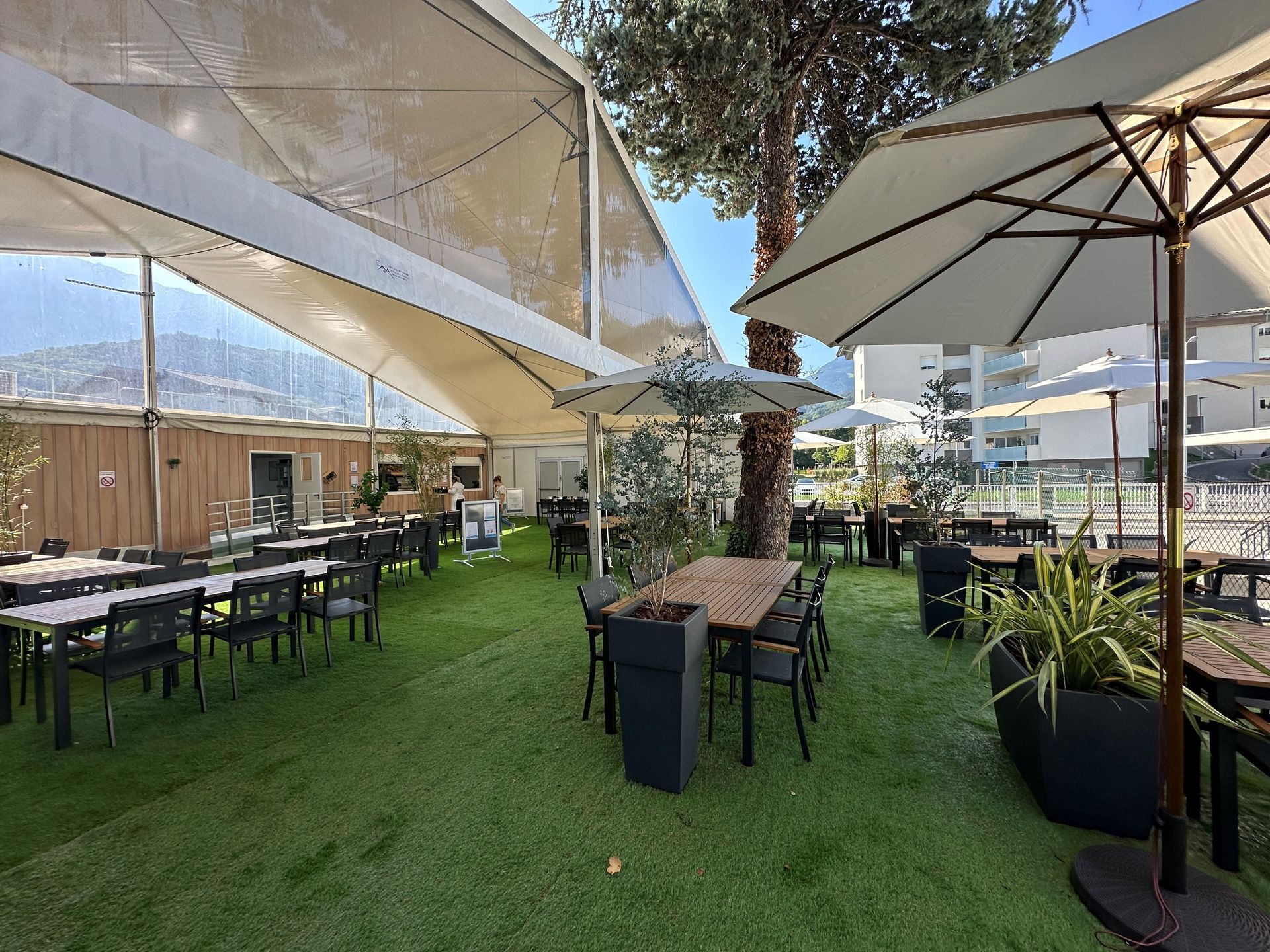 Allée d'un salon professionnel recouverte de moquette bleue, avec des stands sous une tente blanche.