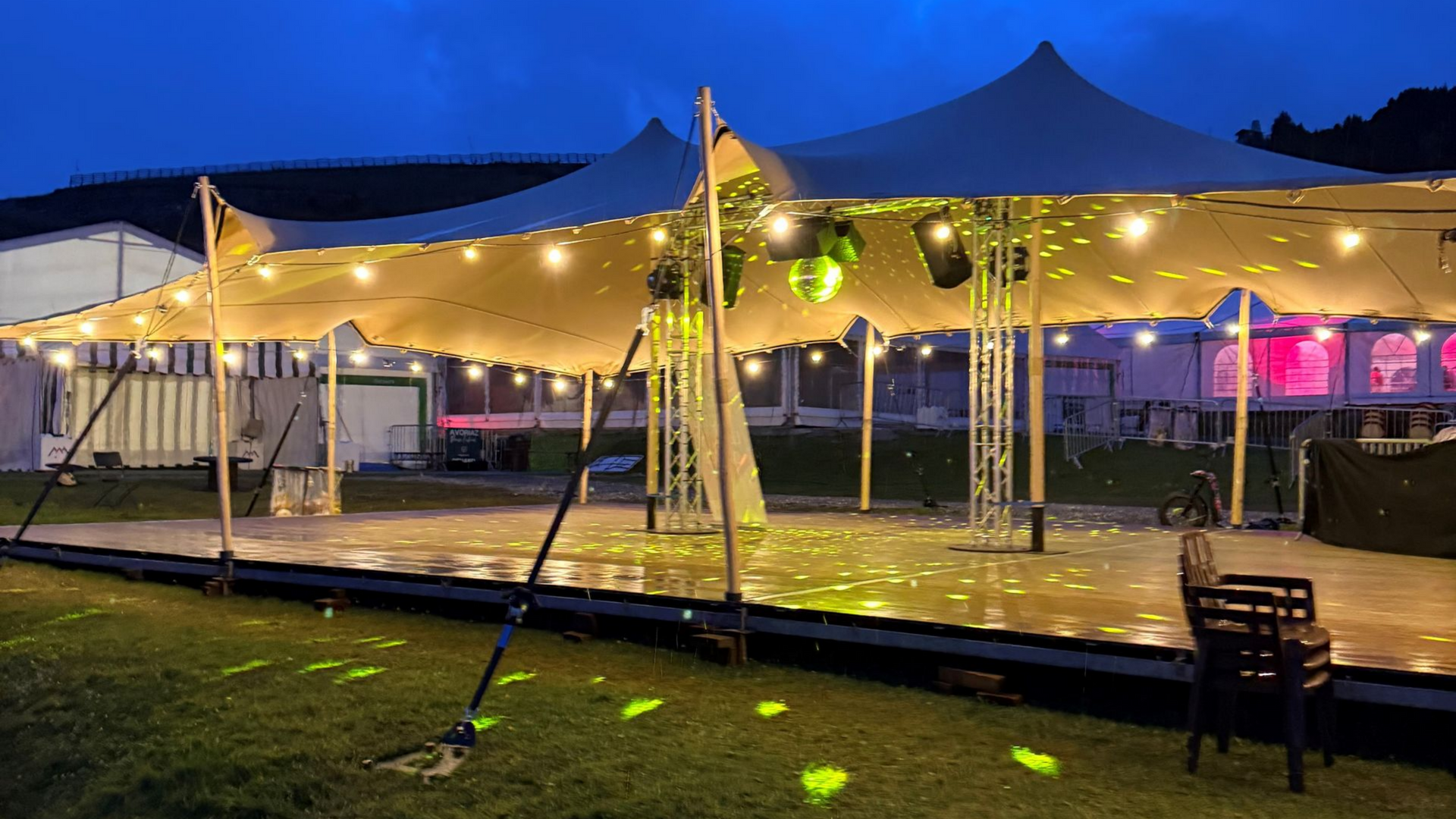 Réception de mariage en plein air sous une canopée marron, tables dressées, illuminées.