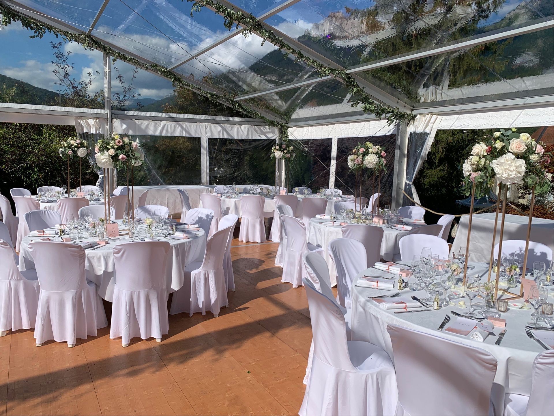 Table pliante ronde blanche avec des pieds en métal gris, sur fond blanc uni.