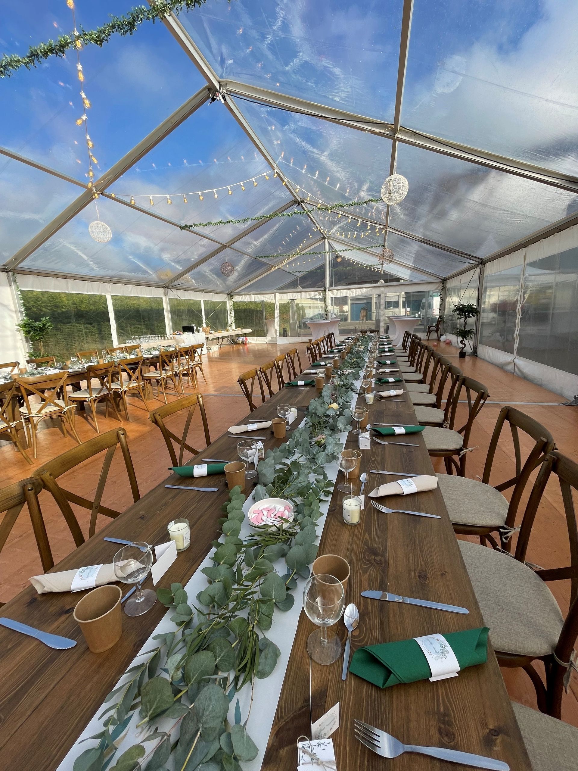 Intérieur lumineux de la tente avec mobilier blanc sur sol bleu, donnant sur un lac.